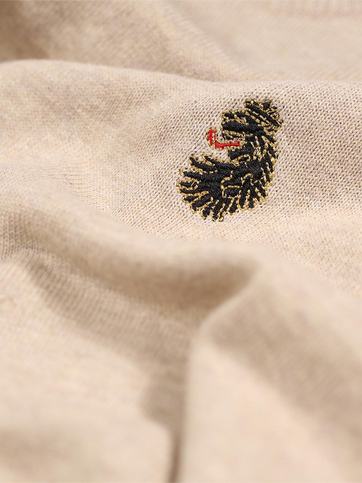 Close-up of LUKE 1977 lion head embroidery on chest of stone marle Gerard knitted jumper