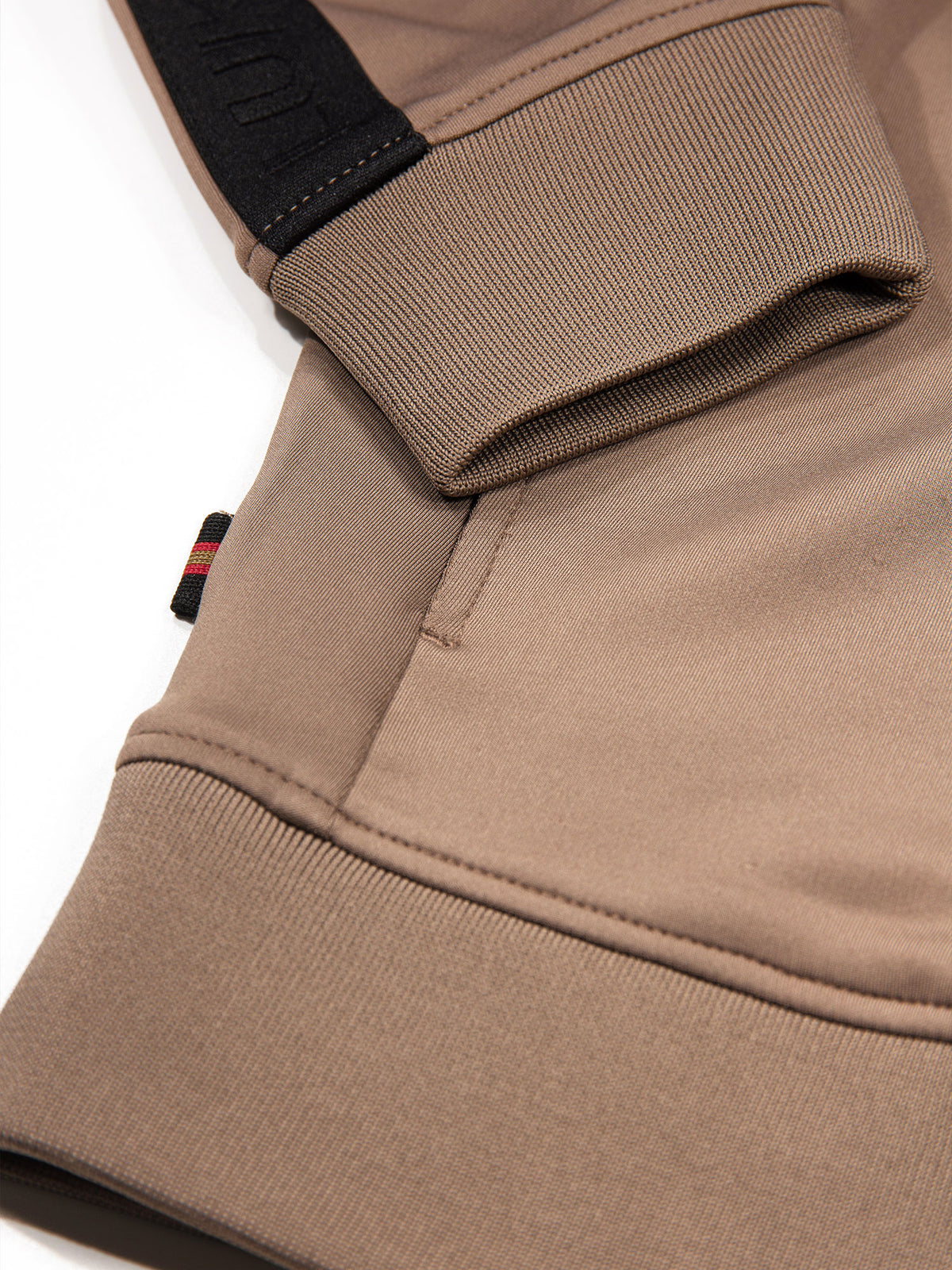Close-up of rib trim on brown TTTQR quarter zip sweatshirt