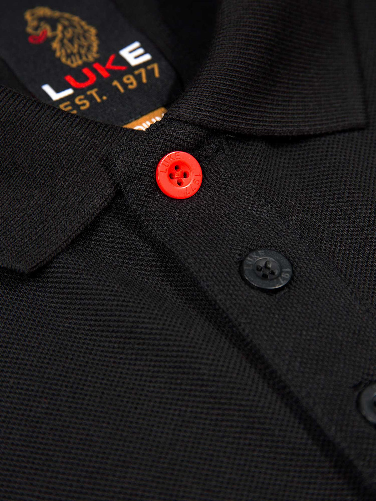 Close-up of rib collar, LUKE EST. 1977 neck label and red top button on black Willtape polo