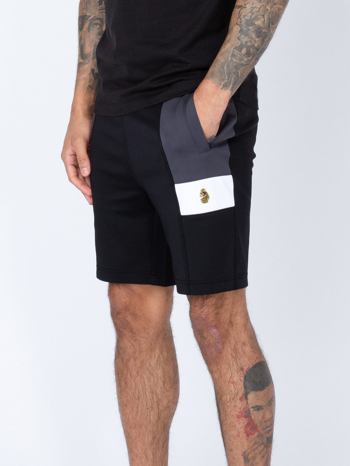 A pair of men's black sweat shorts with a drawcord waistband, front zip pockets, and contrast panels. Featuring the LUKE 1977 lion head embroidery on the left leg.