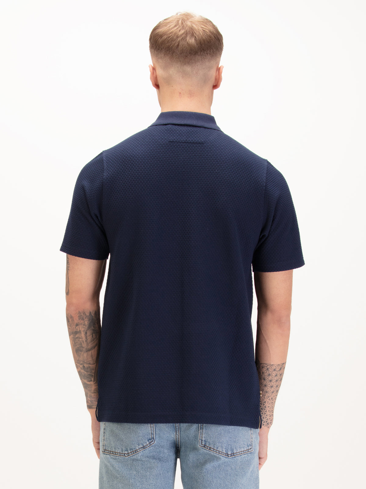 Men's navy polo shirt with zip collar, worn by model, back view