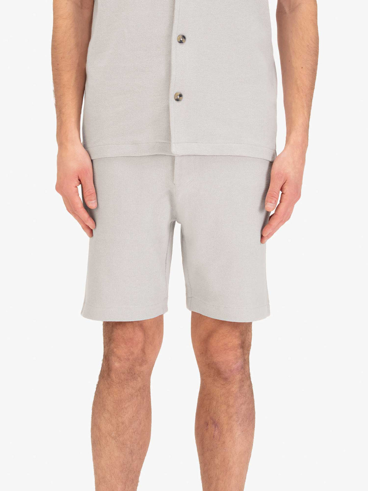 Men's grey shorts with drawstring waistband, worn by a model, front view
