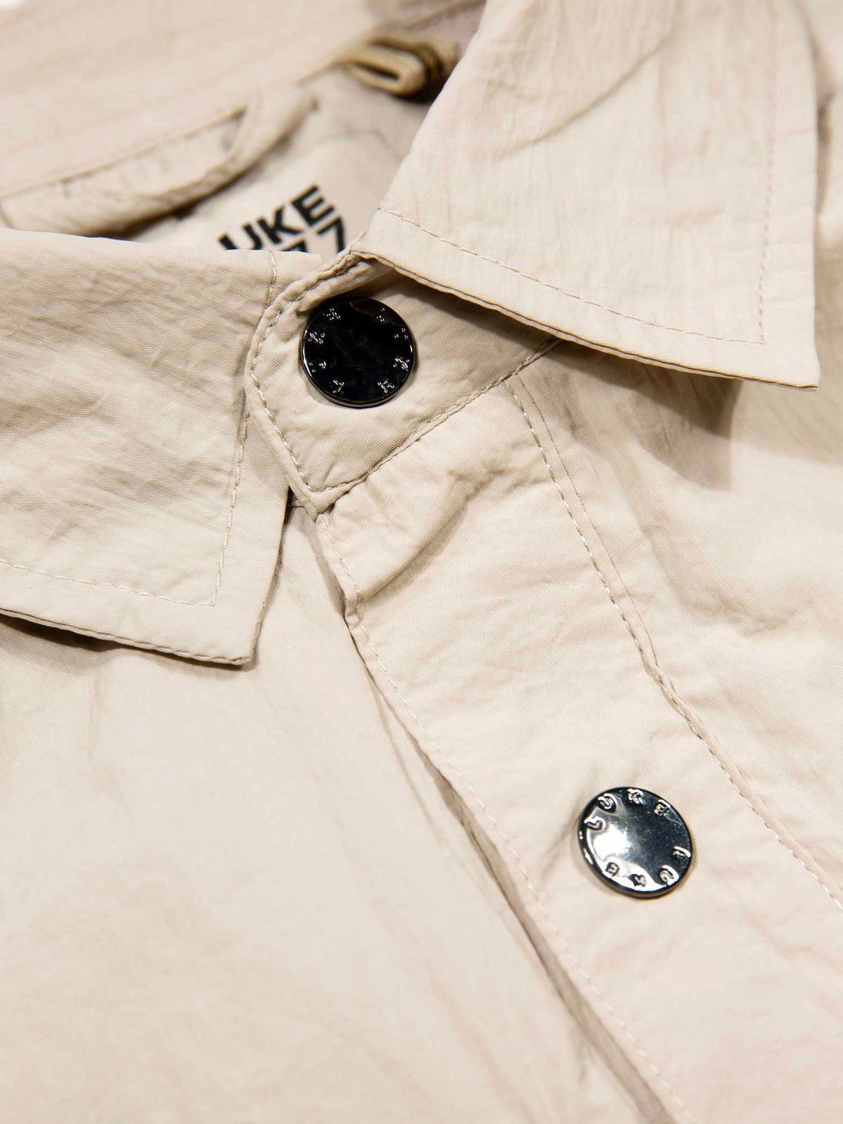 Men's beige jacket with button-up front and chest pocket, detail view