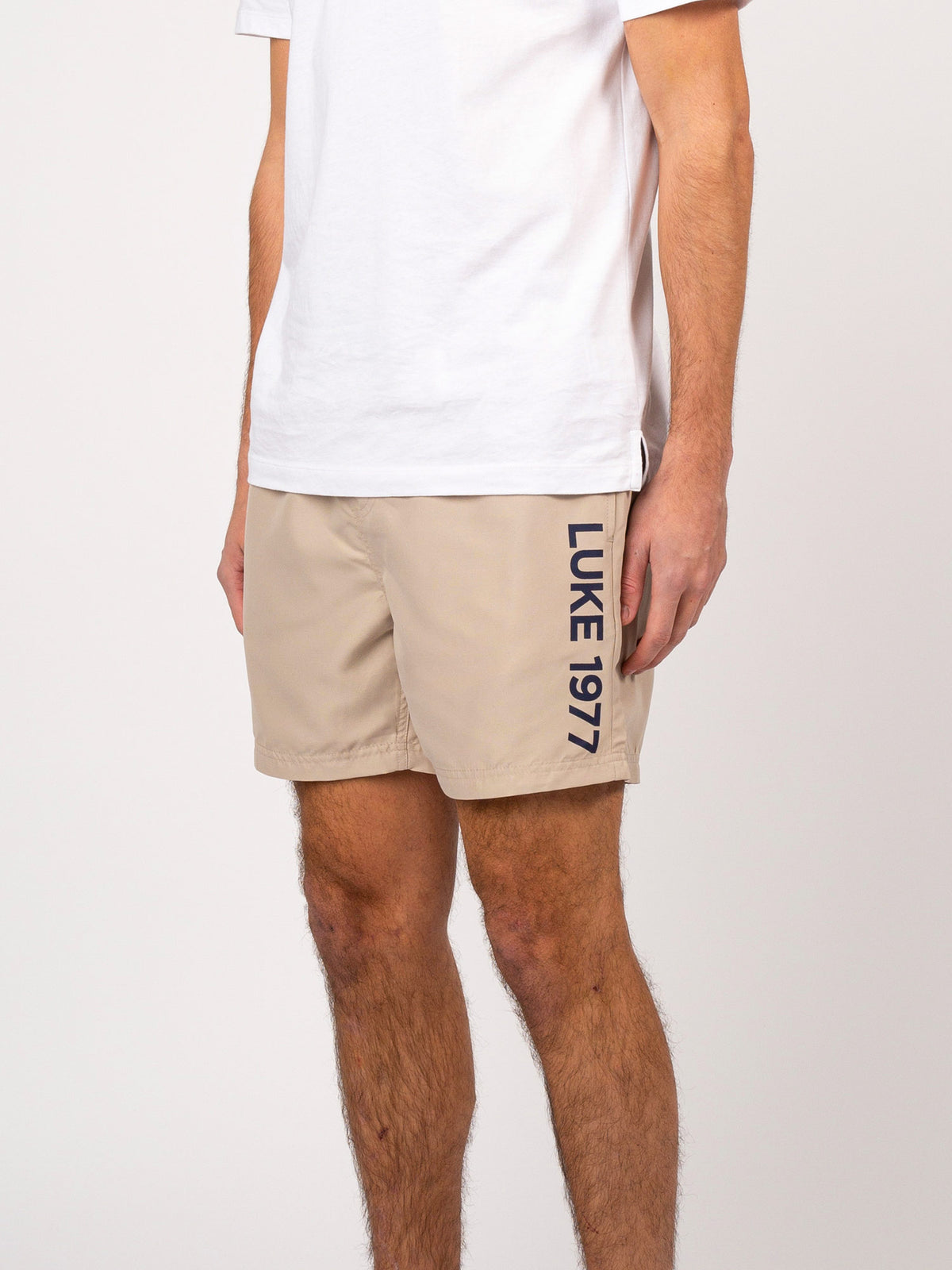 Men's beige swim shorts with drawstring waistband.