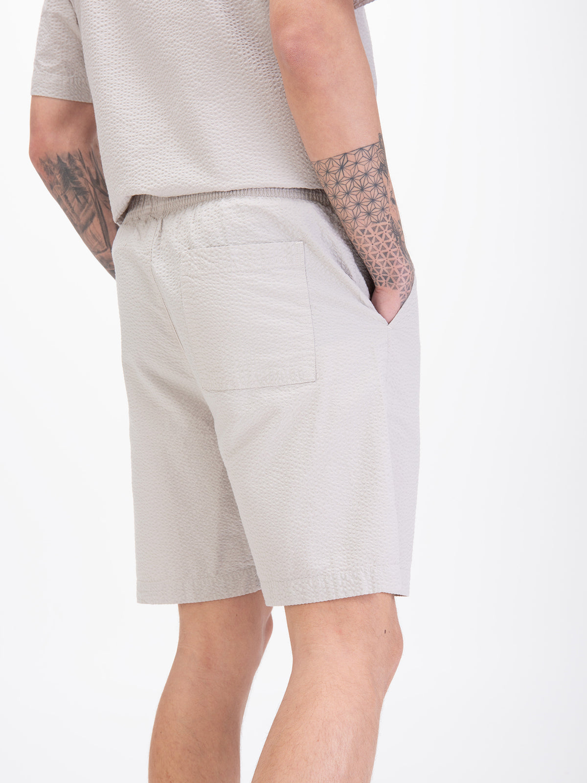 Men's grey shorts with drawstring waistband, worn by a model, detail view