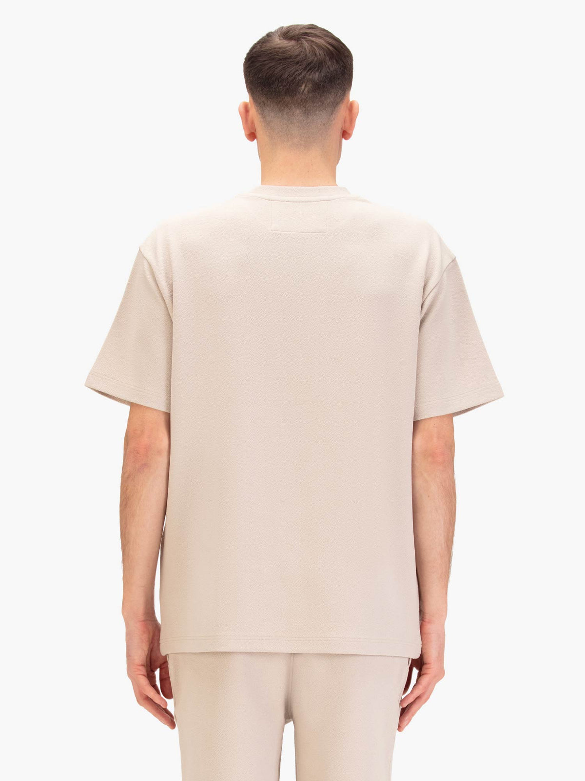 Men's relaxed-fit beige t-shirt with crew neck and short sleeves, worn by a model, back view