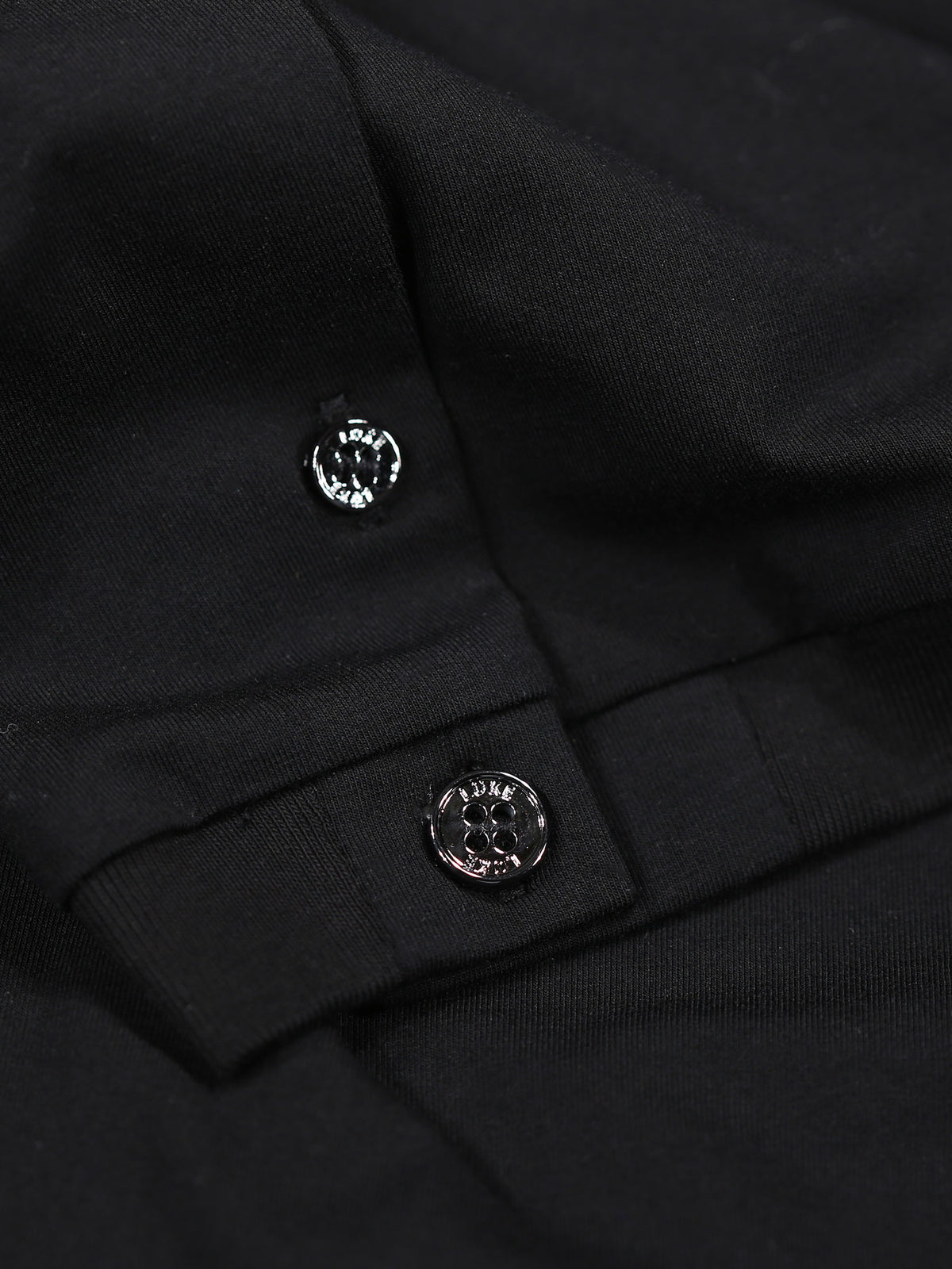 Close-up of shiny buttons on sleeve cuff of black LUKE 1977 Macau polo shirt