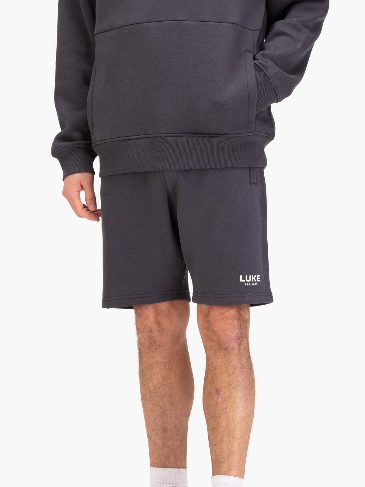 Men's grey shorts with drawstring waistband, worn by a model, front view