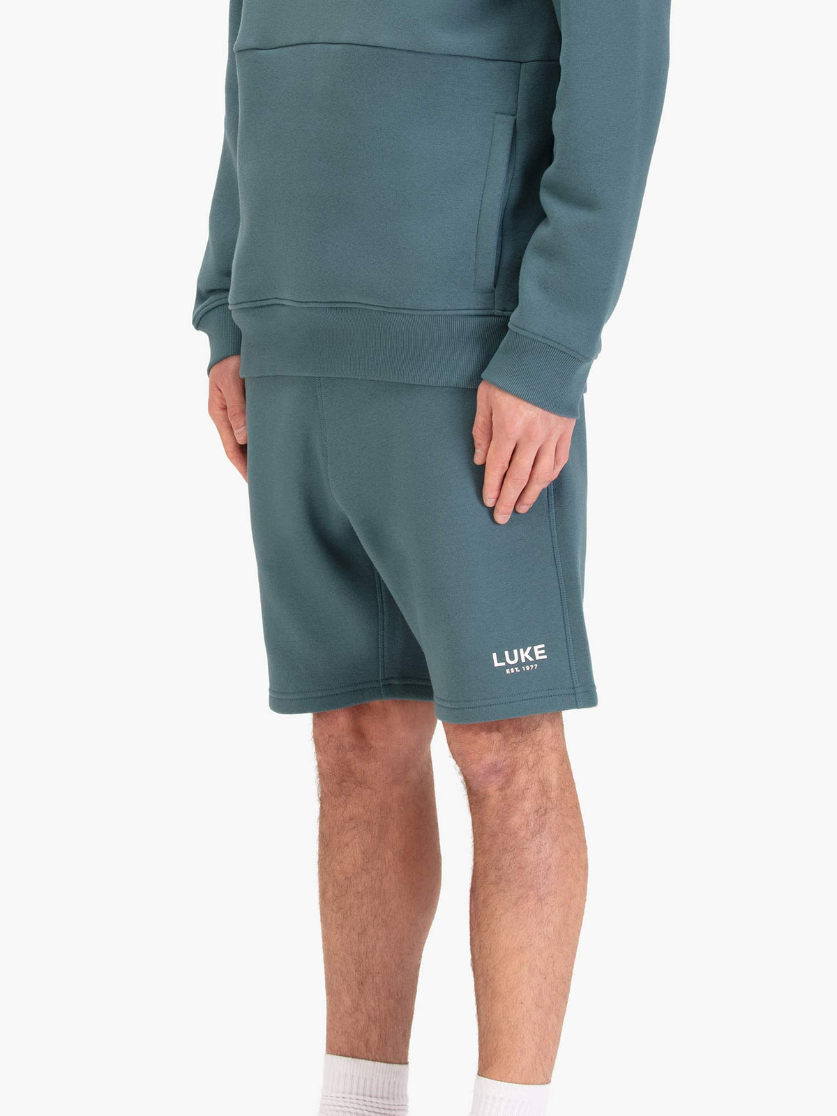 Men's blue shorts with drawstring waistband, worn by a model, side view
