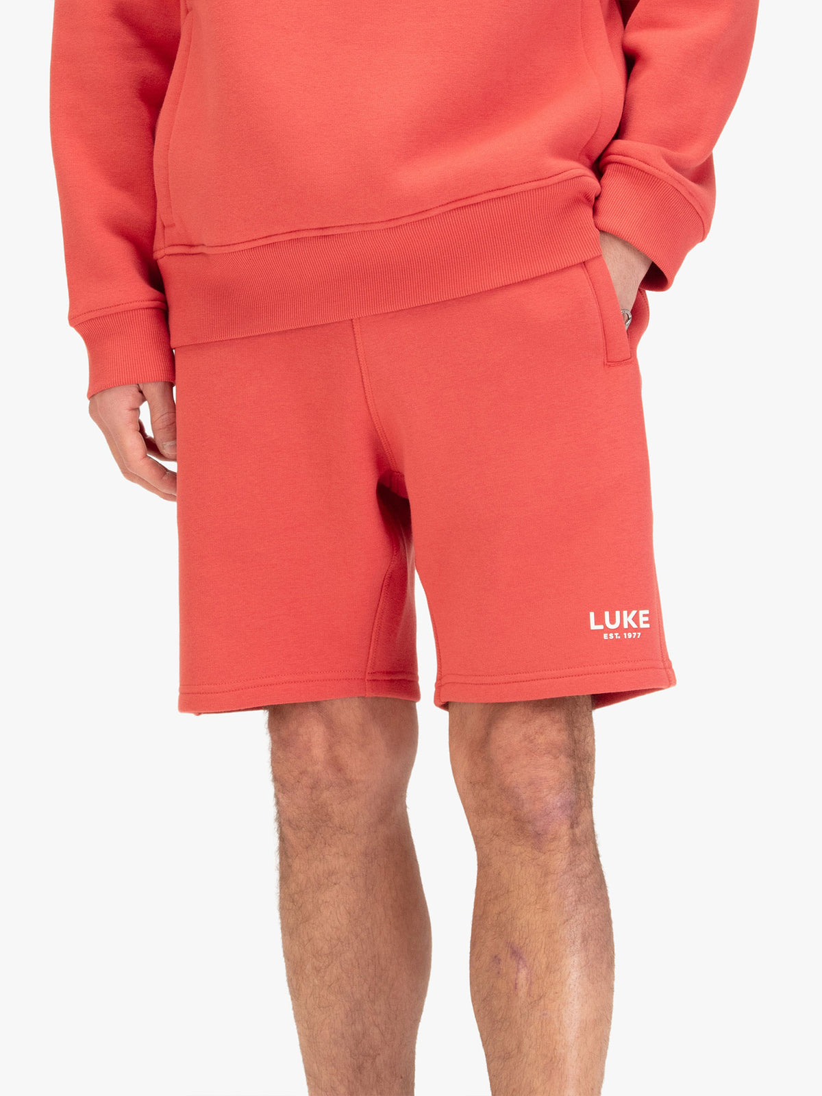 Men's red shorts with drawstring waistband, worn by a model, front view