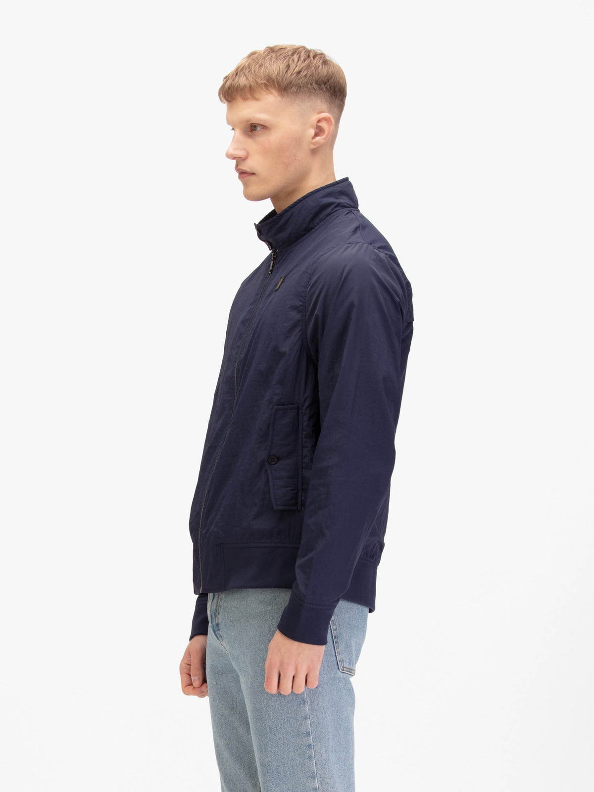 Men's navy jacket with zip-up front and front pocket, worn by a model, side view