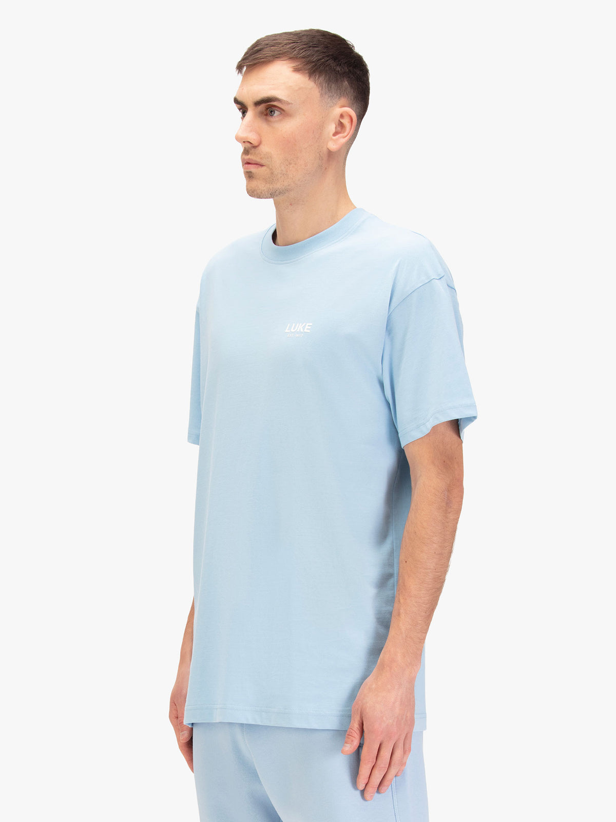 Men's relaxed-fit blue t-shirt with crew neck and short sleeves, worn by a model, side view