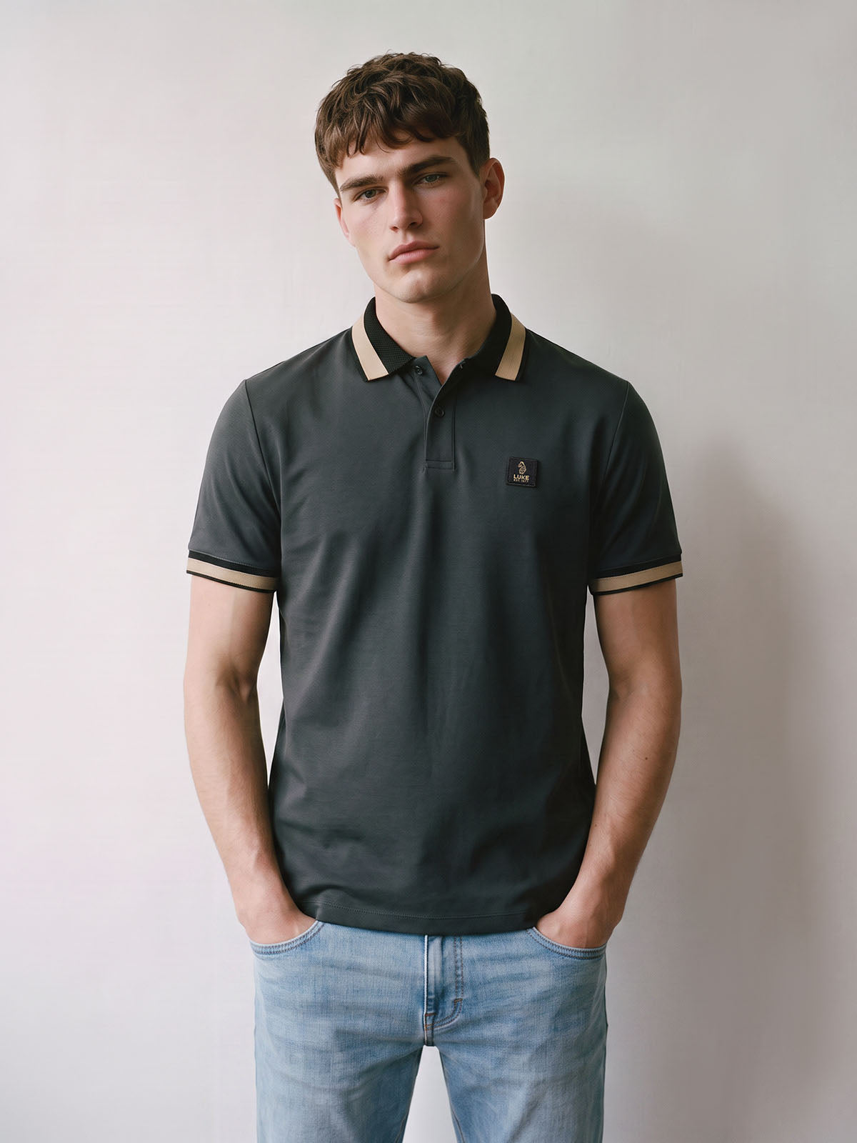 Man wearing charcoal LUKE 1977 Makati pique polo shirt with jeans, front view