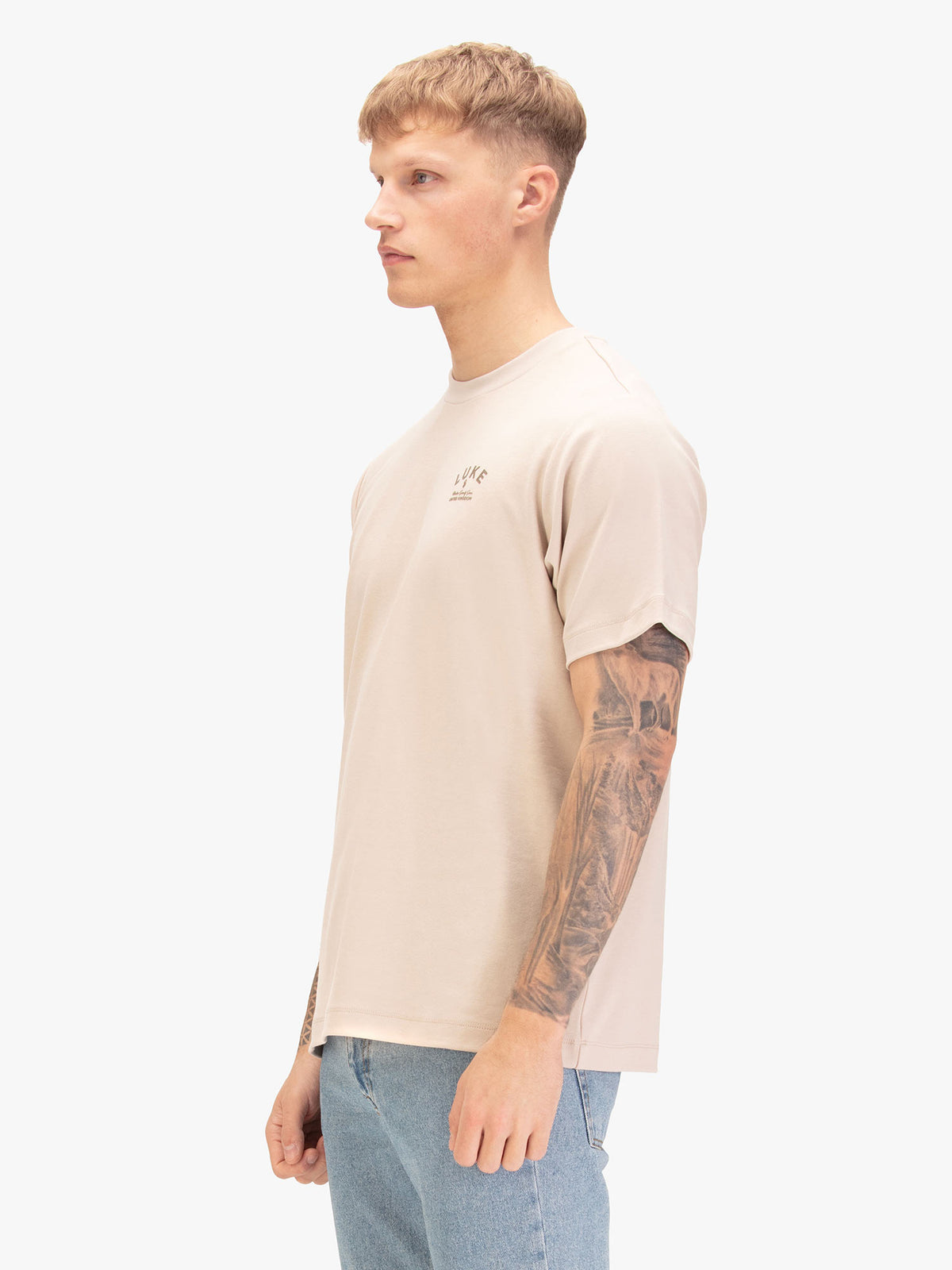 Men's relaxed-fit beige t-shirt with crew neck and short sleeves, worn by a model, side view