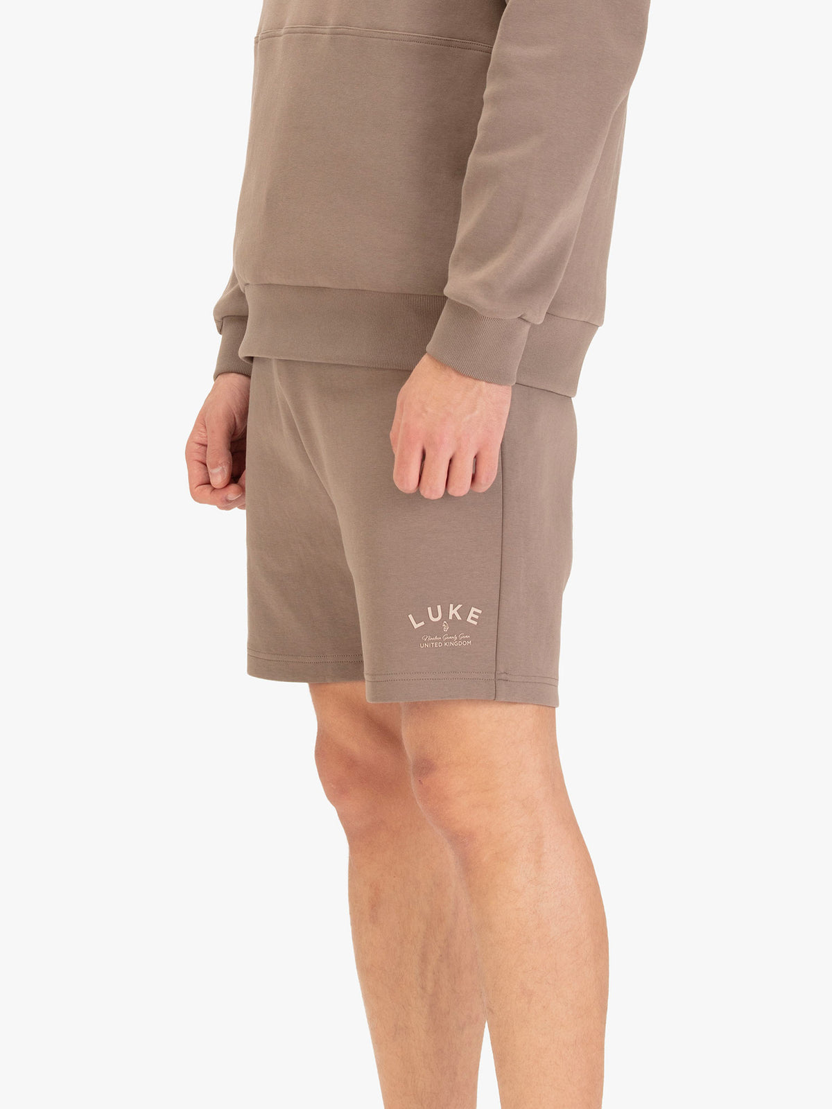 Men's brown shorts with drawstring waistband, worn by a model, side view