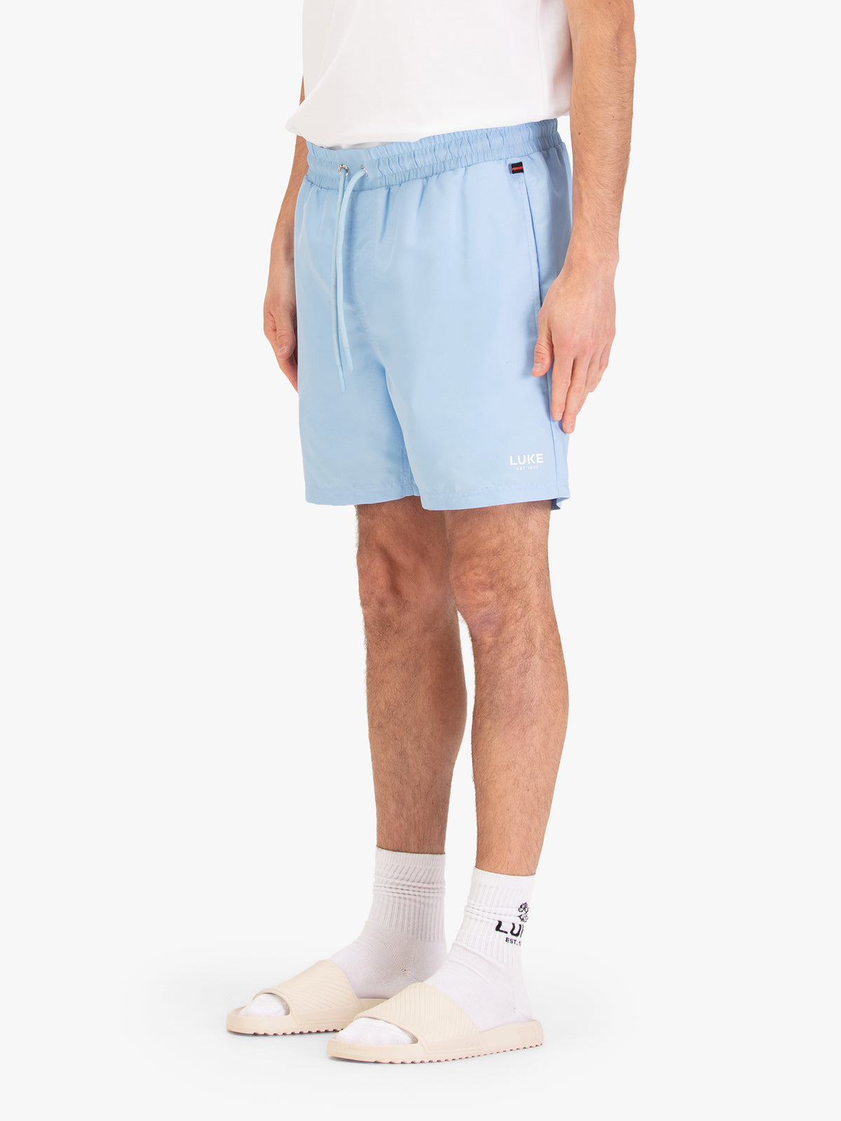 Men's blue-1 swim shorts with drawstring waistband, worn by a model, side view