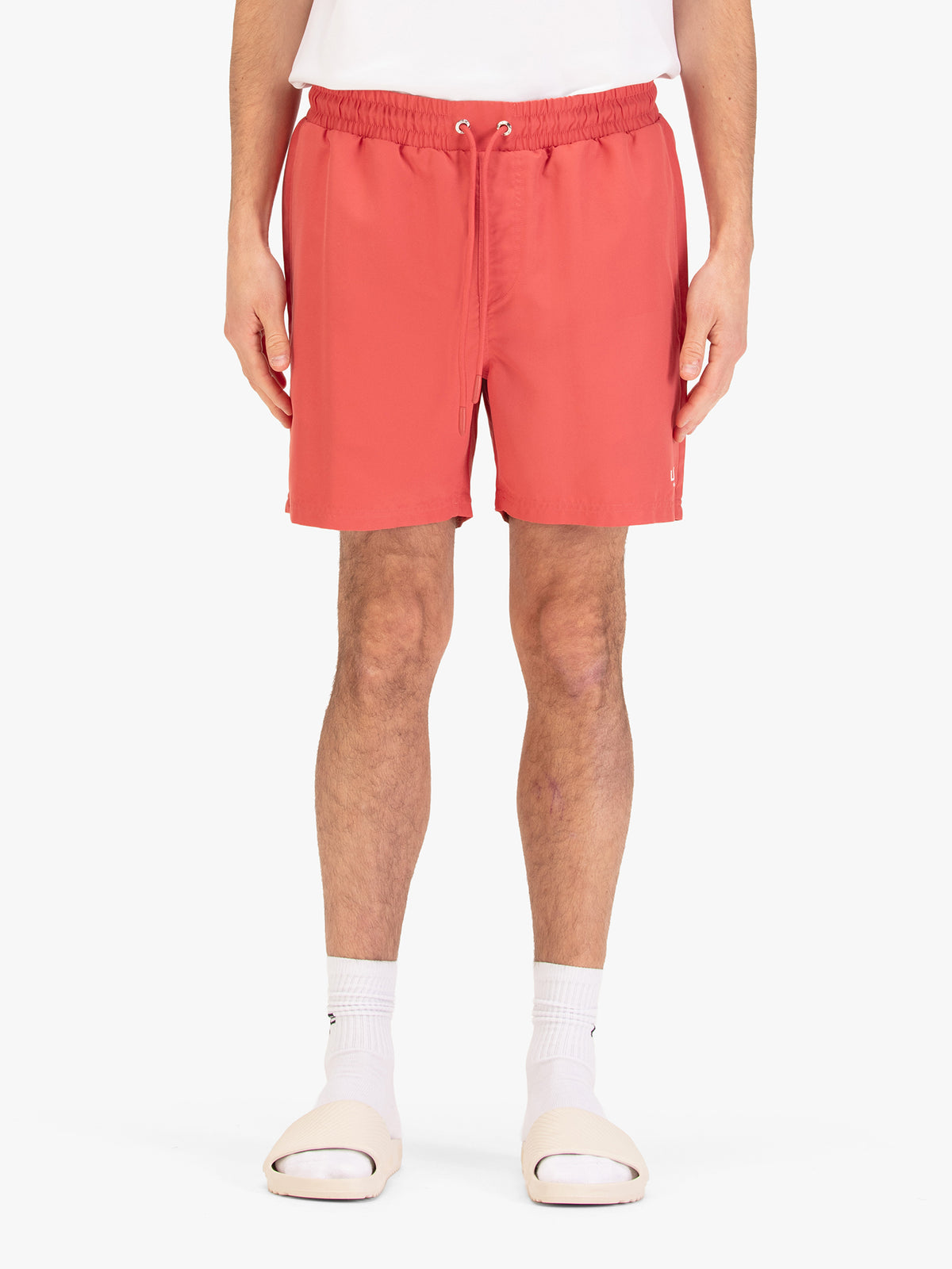 Men's red swim shorts with drawstring waistband, worn by a model, front view