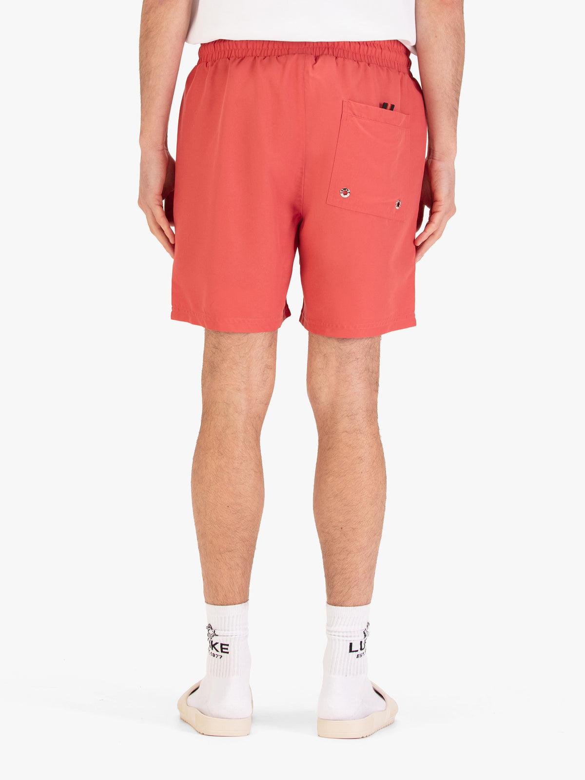 Men's red swim shorts with drawstring waistband, worn by a model, back view