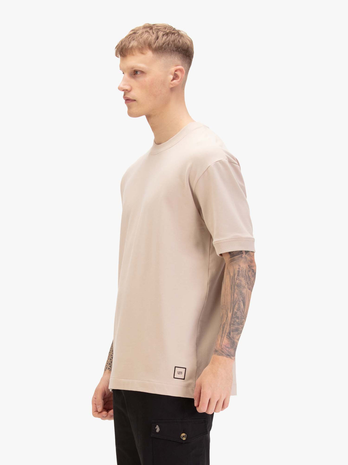 Men's relaxed-fit beige t-shirt with crew neck and short sleeves, worn by a model, side view