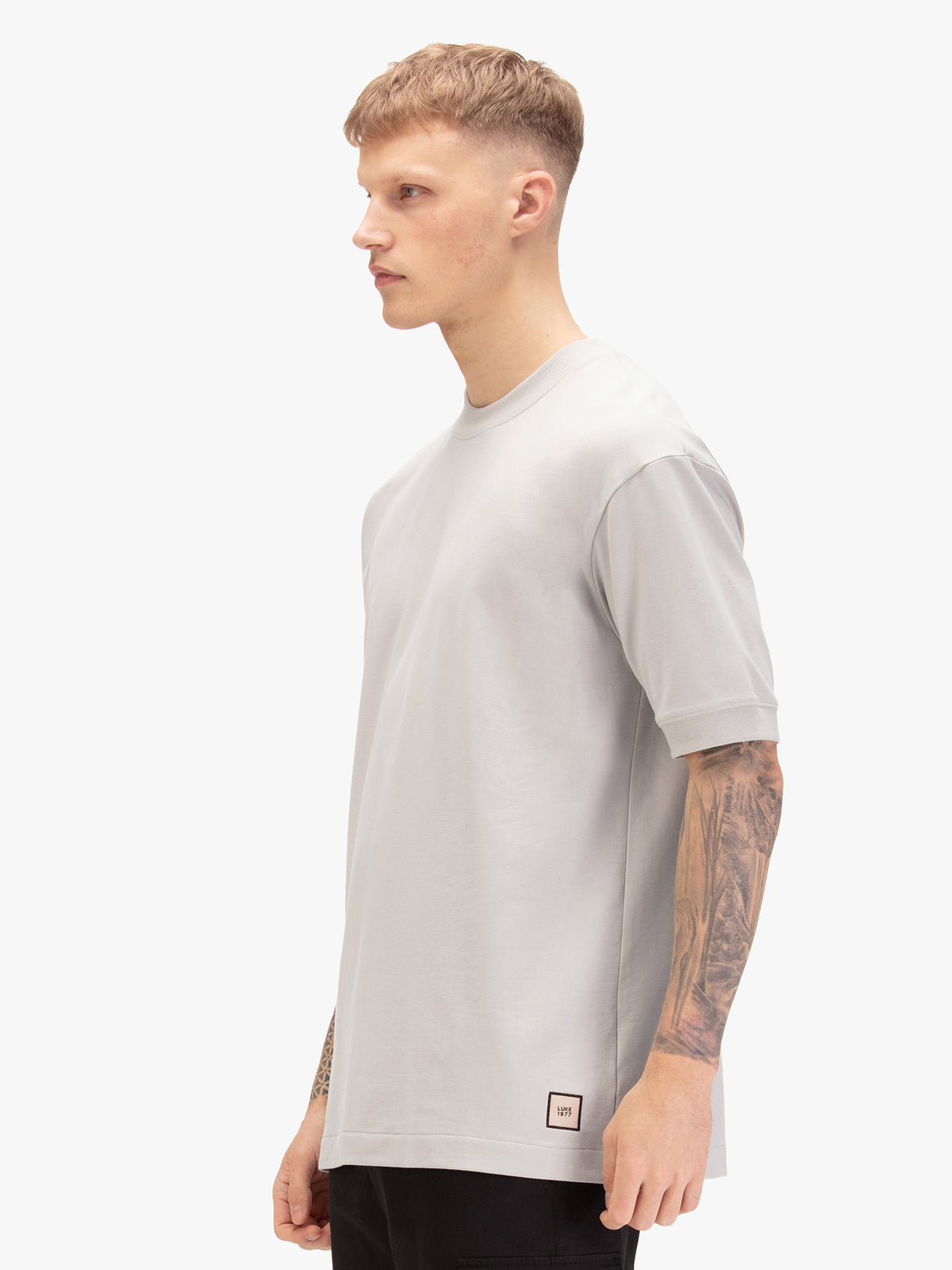 Men's relaxed-fit grey t-shirt with crew neck and short sleeves, worn by a model, side view