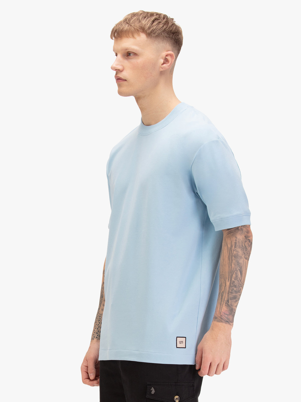 Men's relaxed-fit blue t-shirt with crew neck and short sleeves, worn by a model, side view