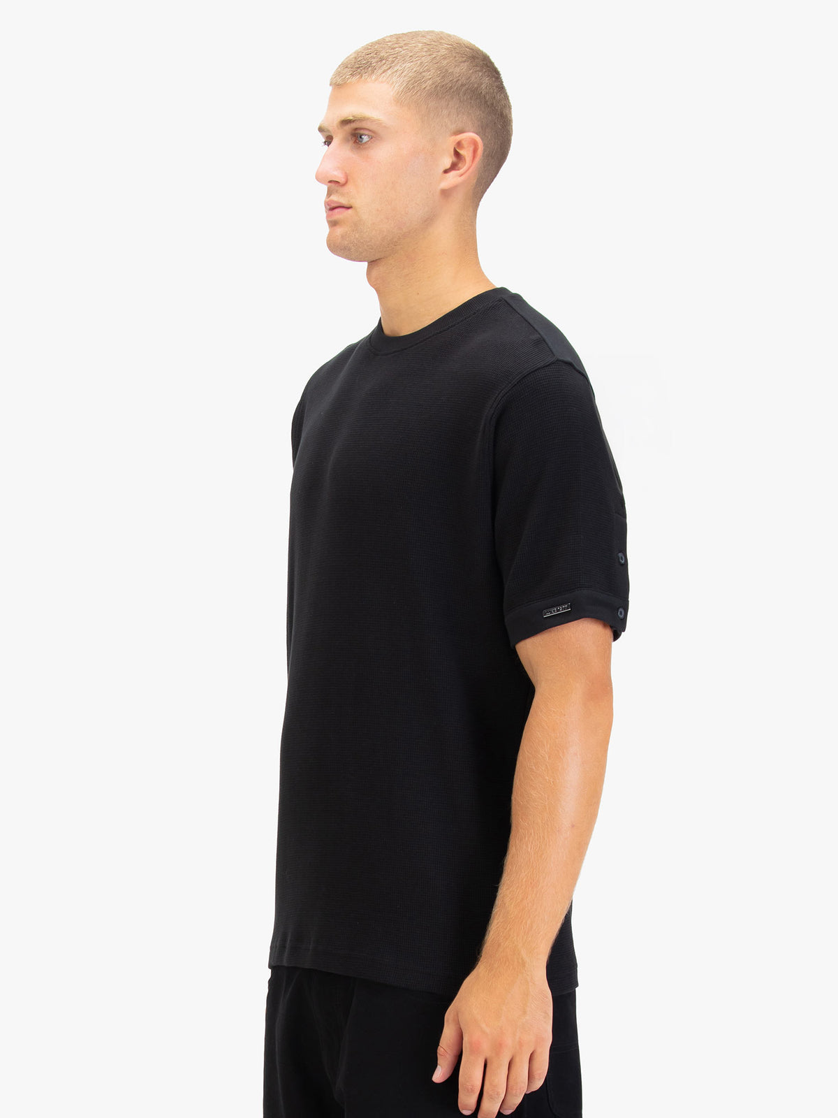 Men's black t-shirt with crew neck and short sleeves worn by a model - side view.