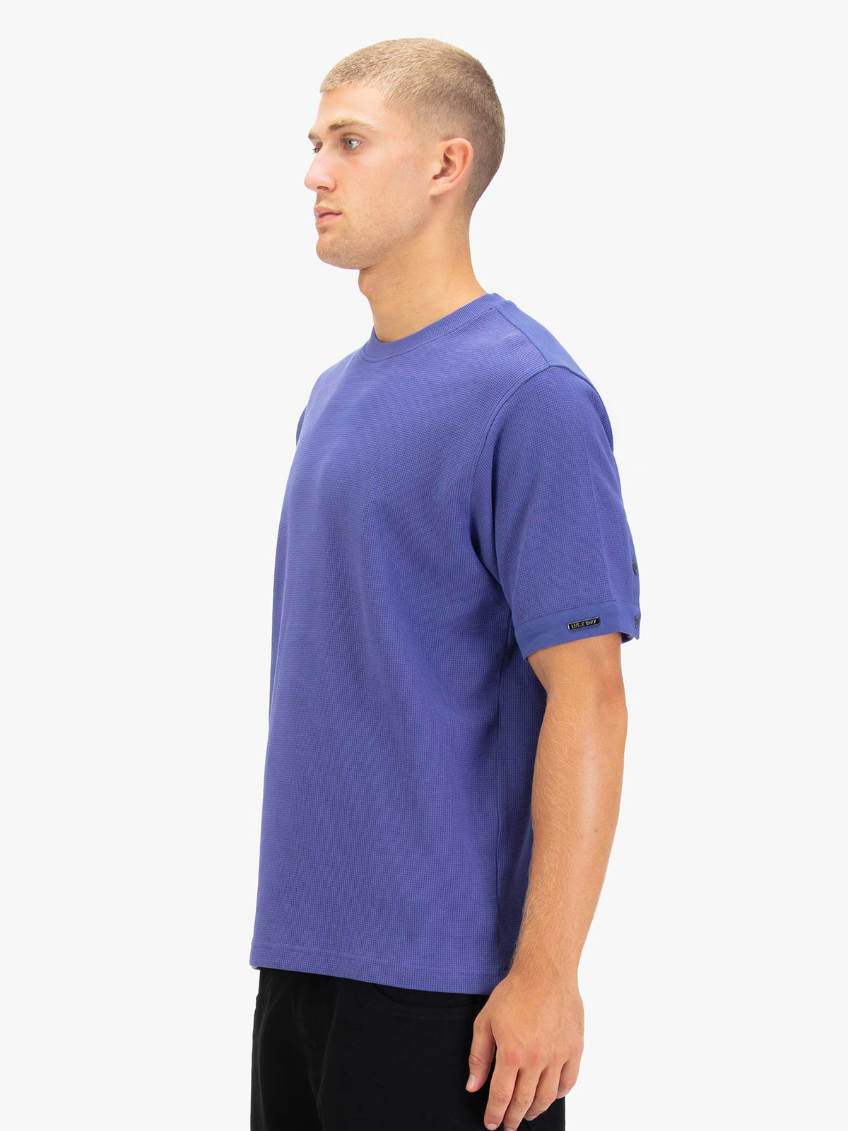 Men's purple t-shirt with crew neck and short sleeves worn by a model - side view.