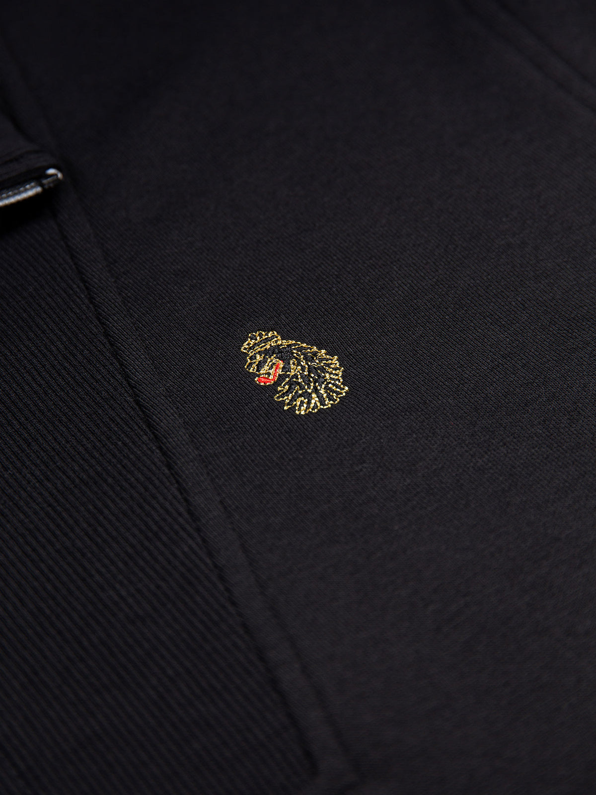Close-up of LUKE lion head embroidery on black Jan Jose sweatshirt