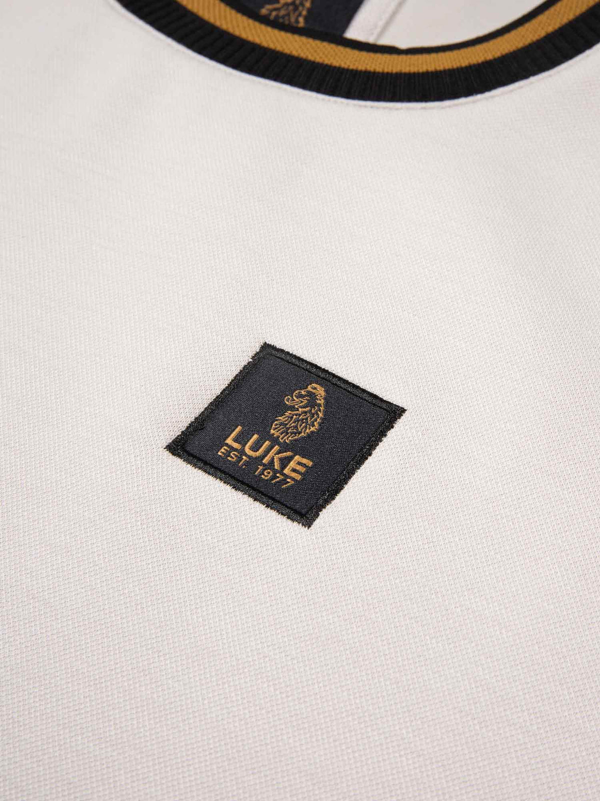 Men's grey tracksuit with sweatshirt and matching joggers, detail view of the badge.