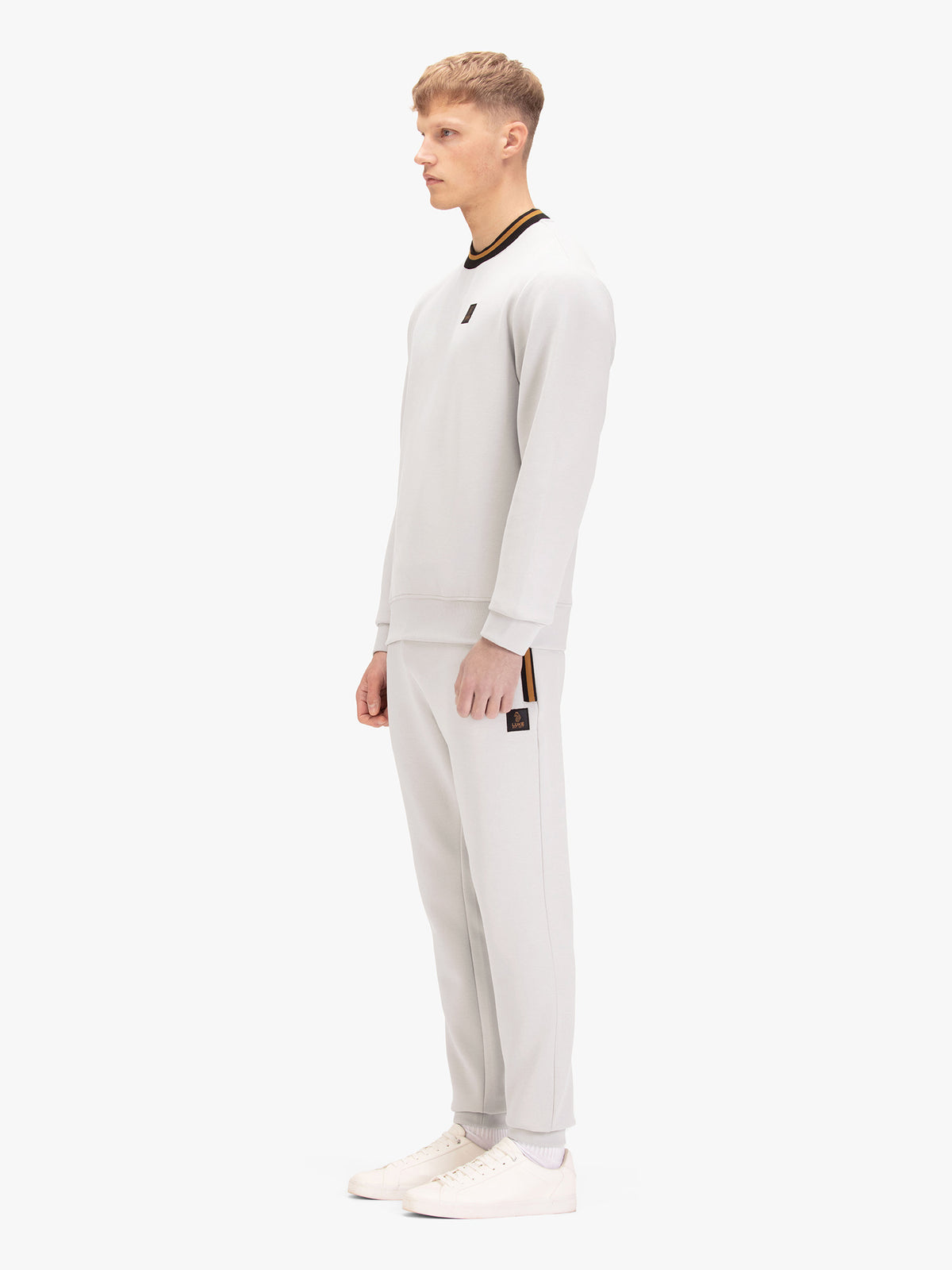 Men's grey tracksuit with sweatshirt and matching joggers, worn by a model, side view.