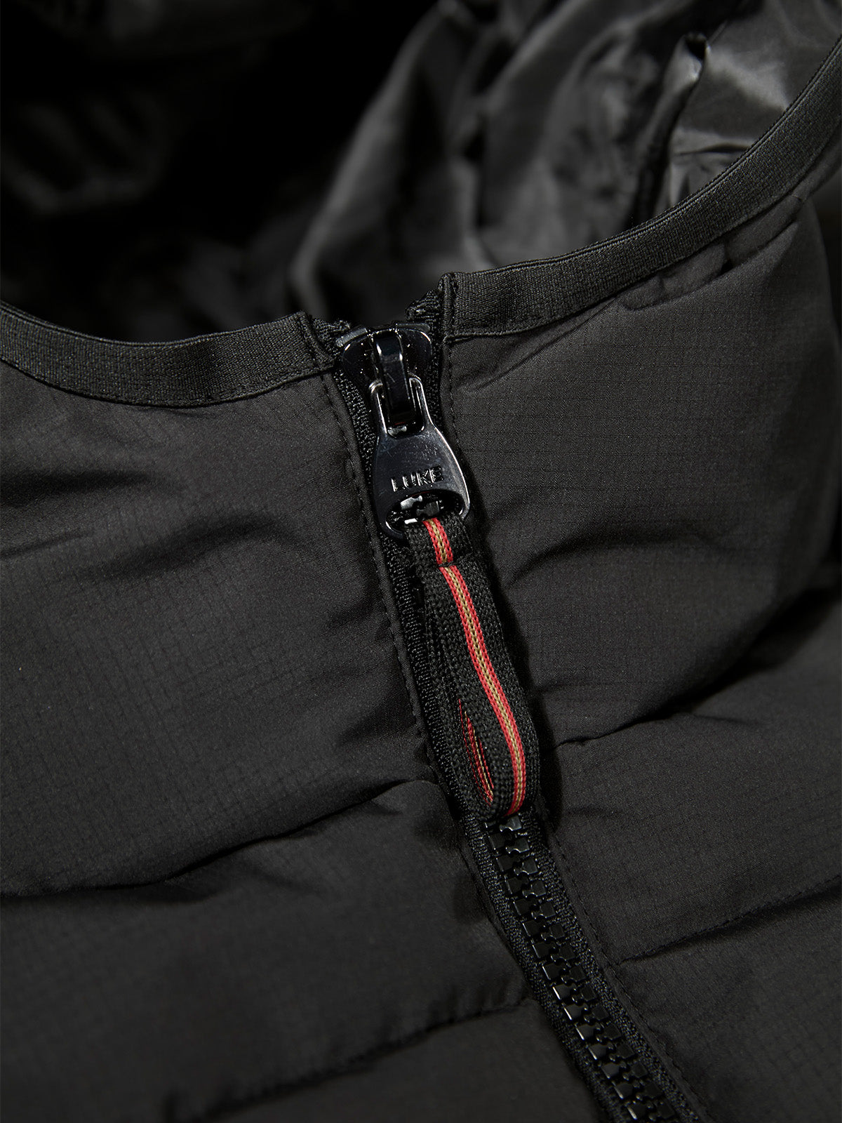 Close-up of zip with tri-colour trim tape at the neck of black Mayor Of Cantoria jacket