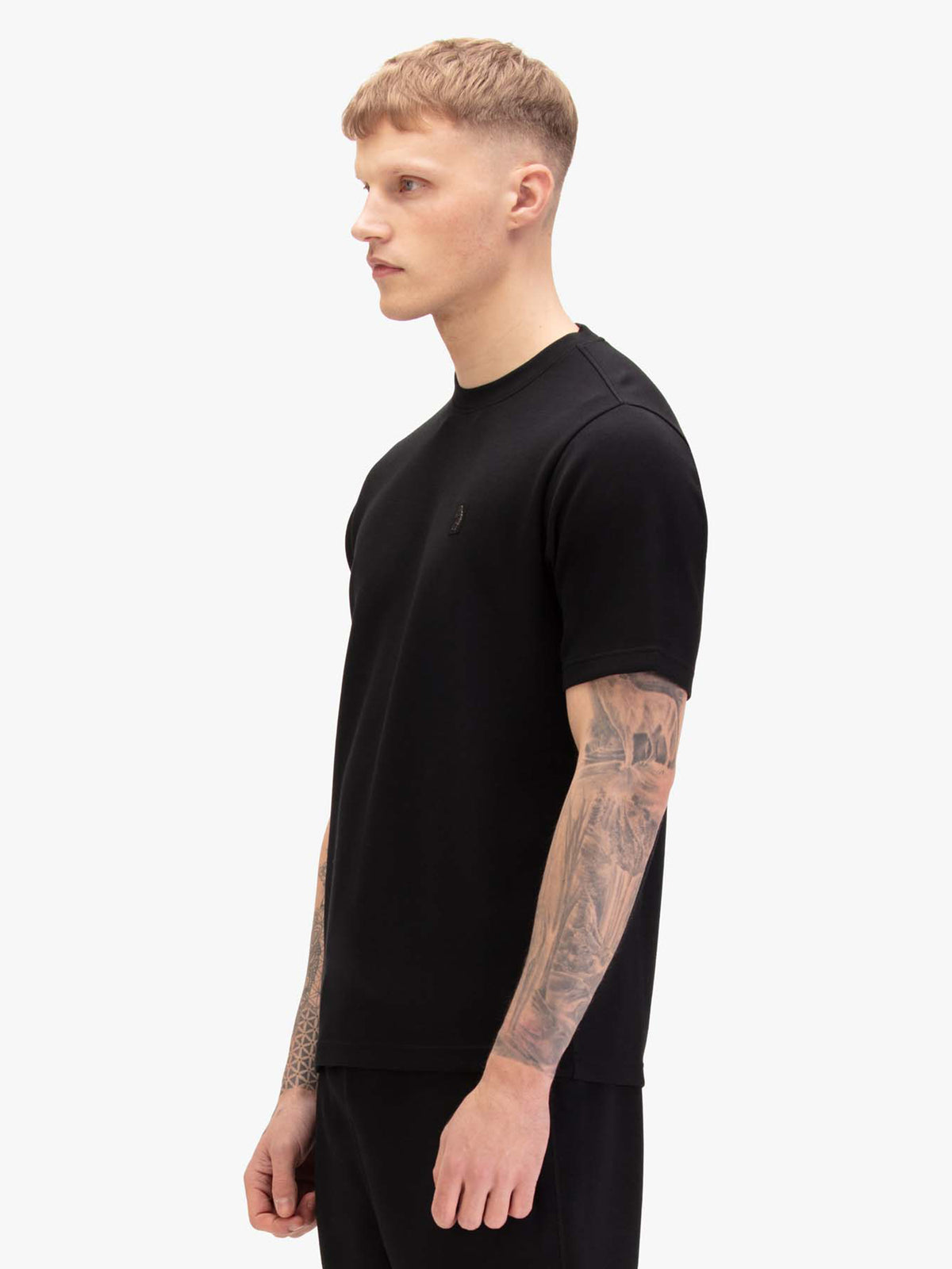 Men's black t-shirt with crew neck and short sleeves, worn by a model, side view