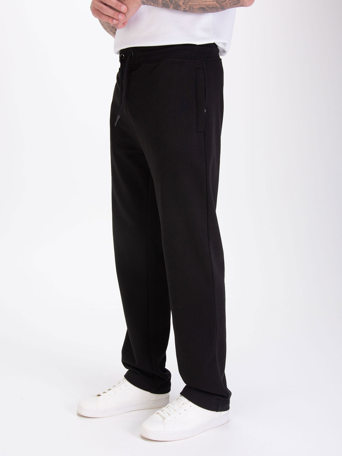 Men's wide-leg black joggers with drawstring waistband, worn by a model, detail view