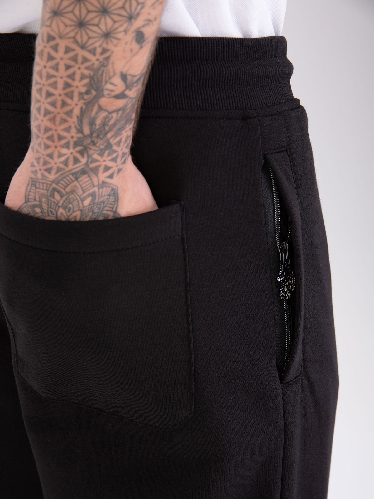 Men's wide-leg black joggers with drawstring waistband, worn by a model, detail view