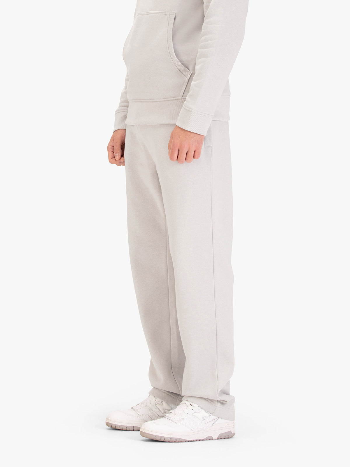 Men's wide-leg grey joggers with drawstring waistband, worn by a model, side view