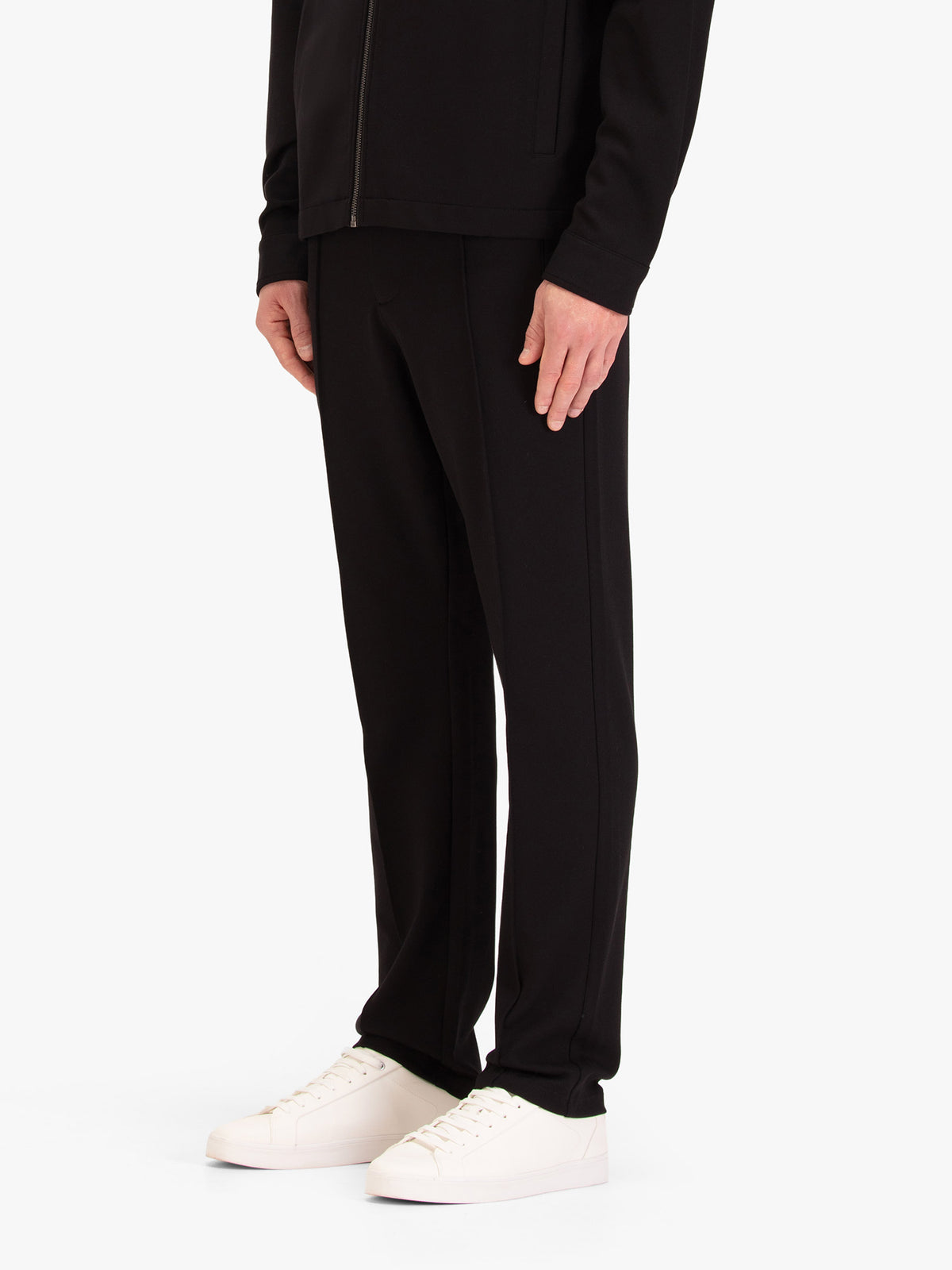 Men's black trousers with drawstring waistband, worn by a model, side view