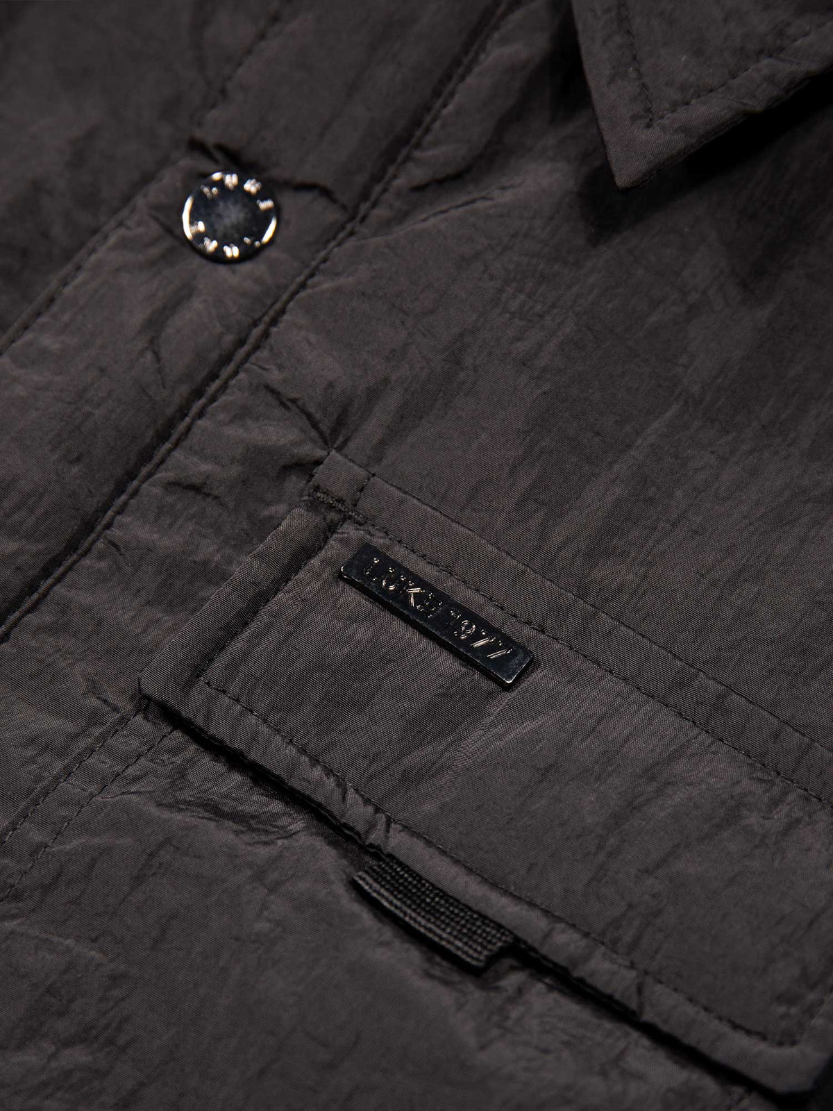 Men's black jacket with button-up front and front pocket, detail view 1
