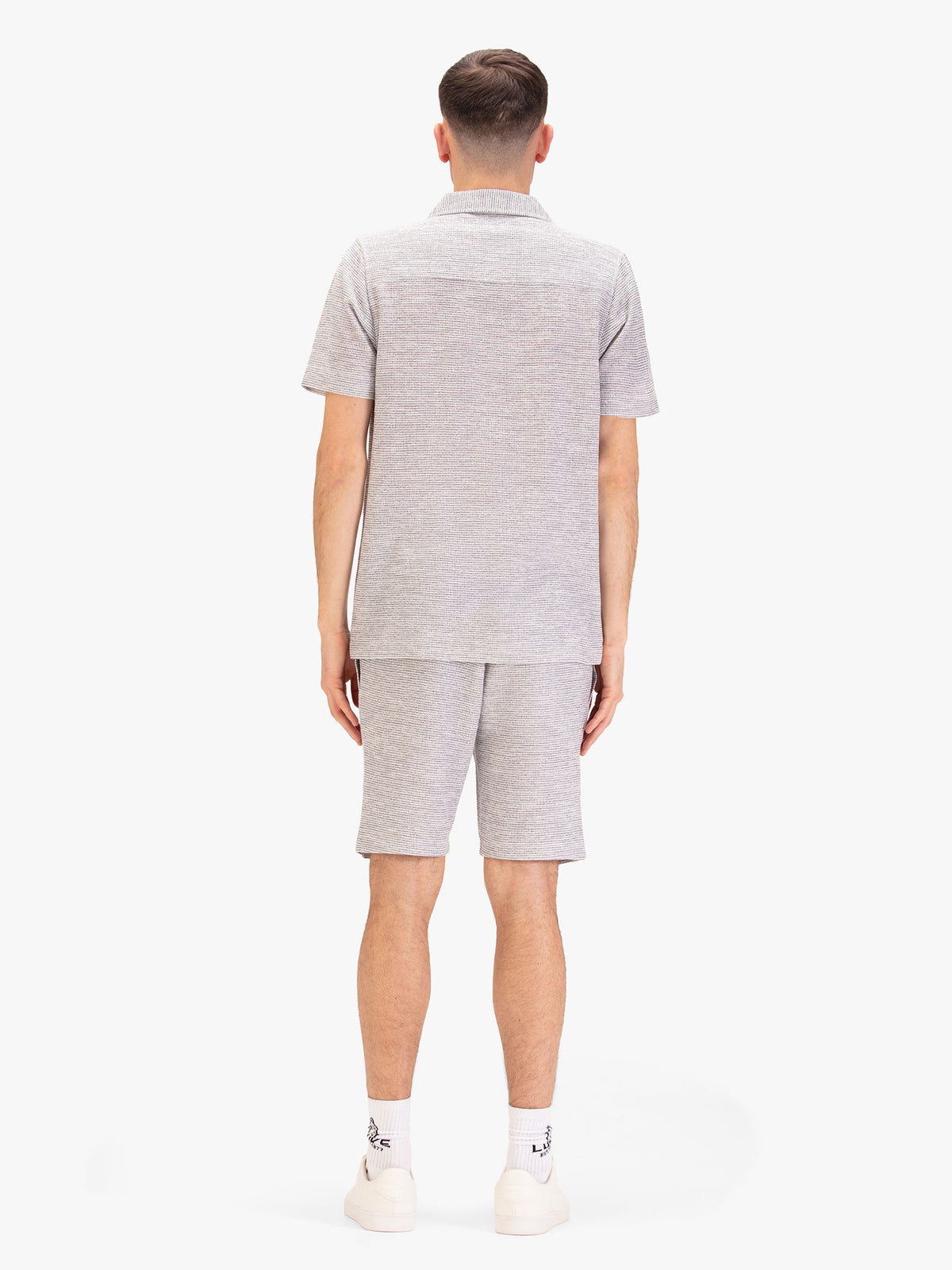 Men's grey short set with short-sleeve shirt and matching shorts, worn by a model, back view.