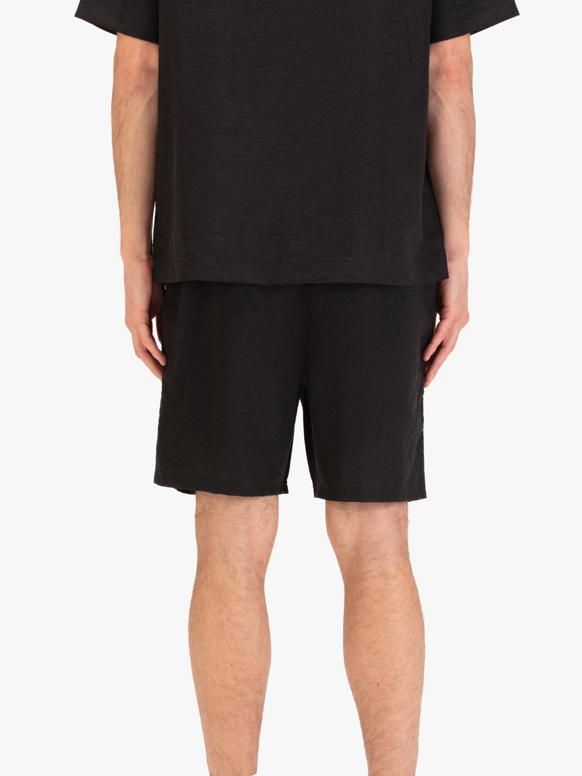 Men's black shorts with drawstring waistband and cargo pockets, worn by a model, back view