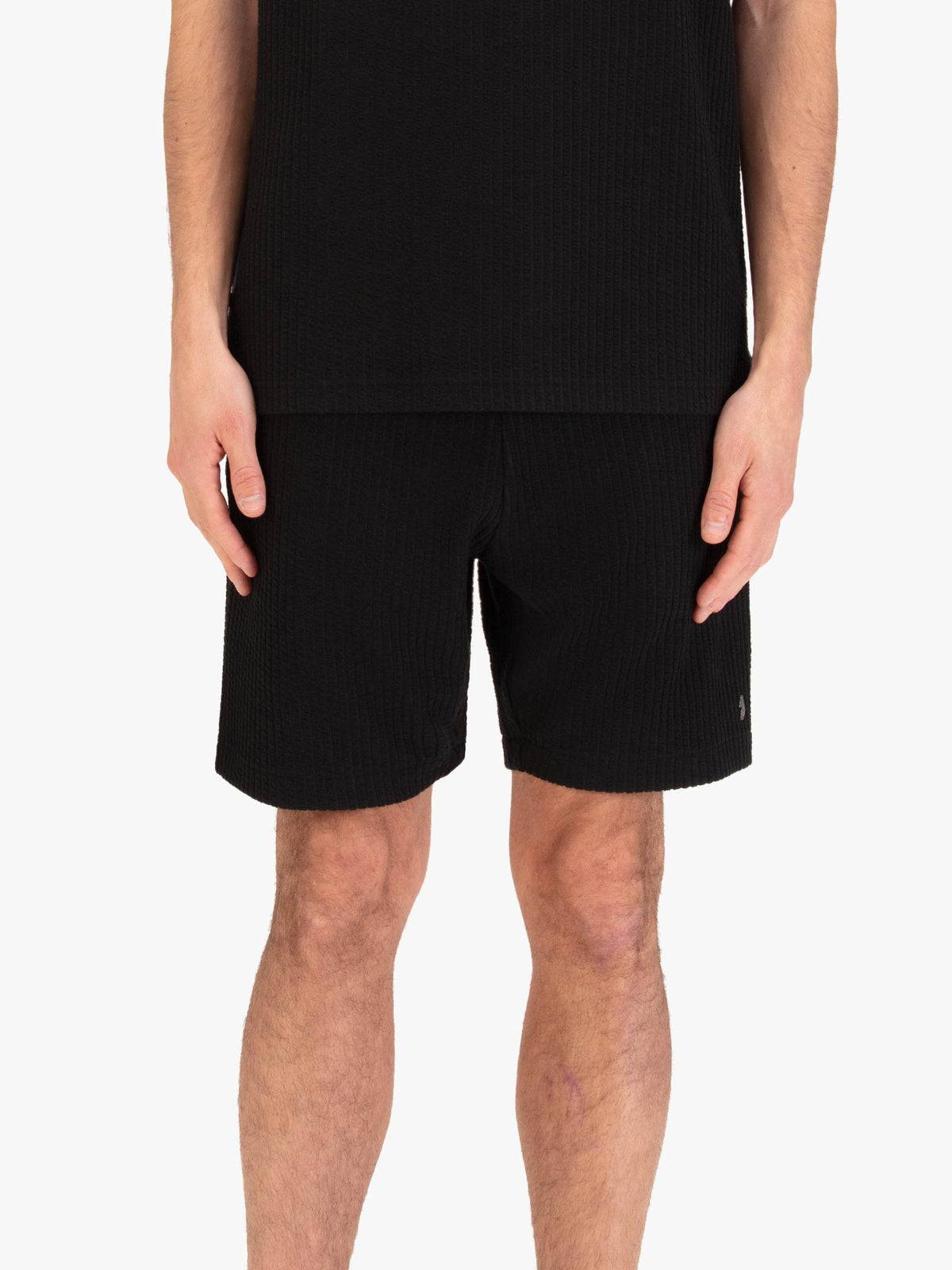 Men's black shorts with drawstring waistband, worn by a model, front view