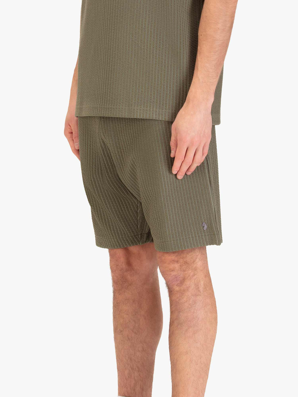 Men's green shorts with drawstring waistband, worn by a model, side view