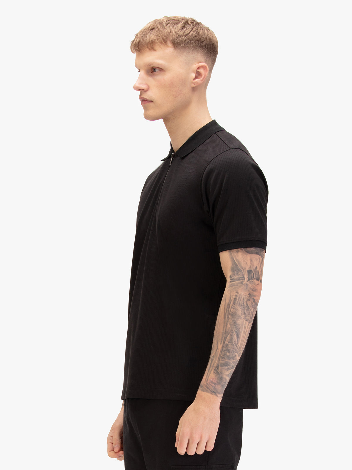 Men's black polo shirt with polo collar, worn by a model, side view
