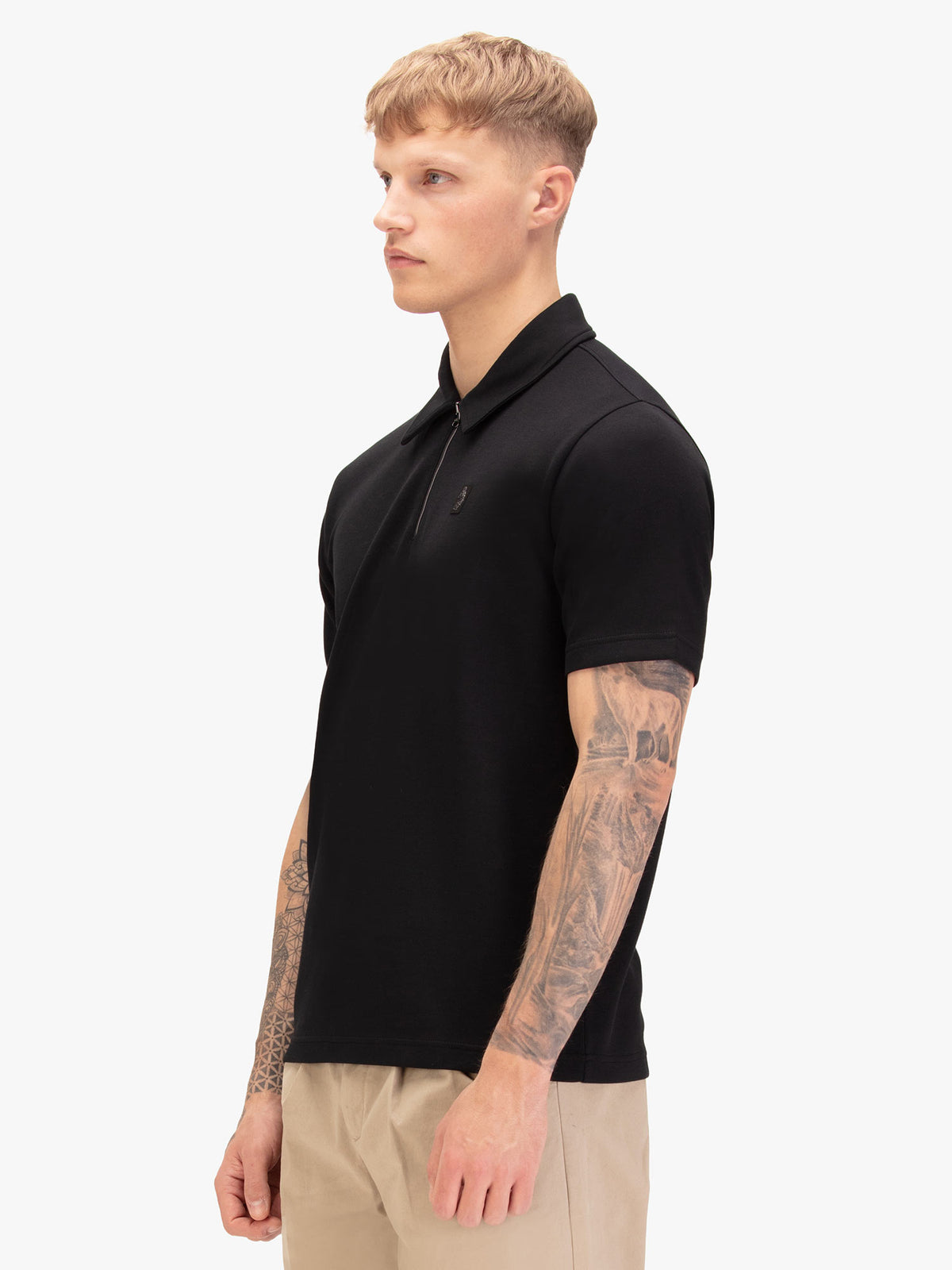 Men's black polo shirt with polo collar, worn by a model, side view