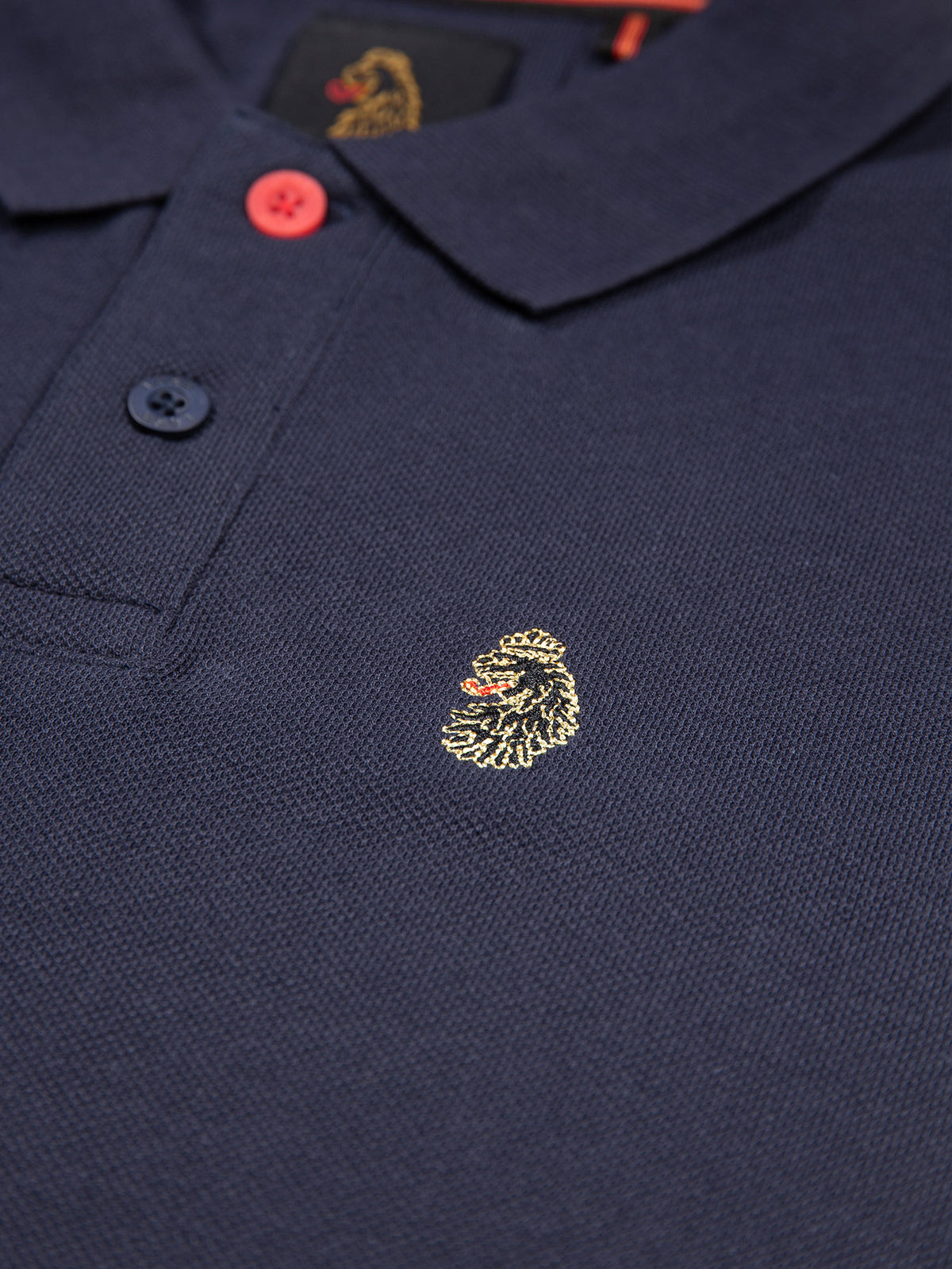 Close-up of LUKE lion embroidery on the chest of navy New Mead cotton piqué polo shirt