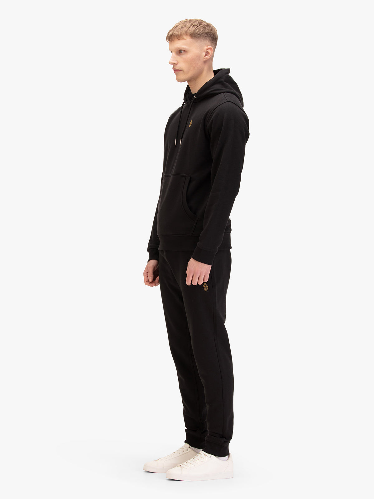Men's black tracksuit with  hoodie and matching joggers, worn by a model, side view