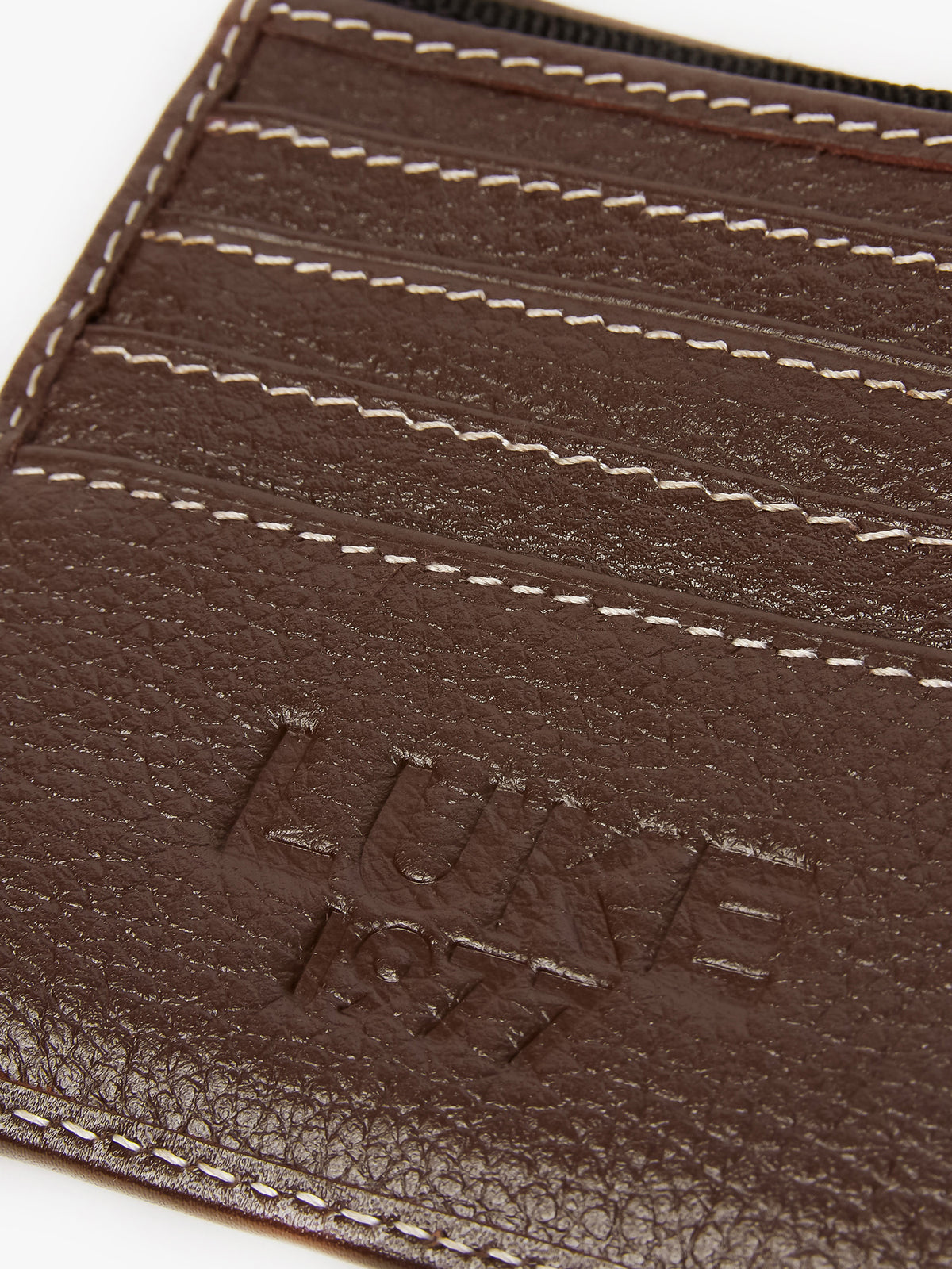 Close-up of debossed LUKE 1977 text and card slots inside brown Volcombe wallet