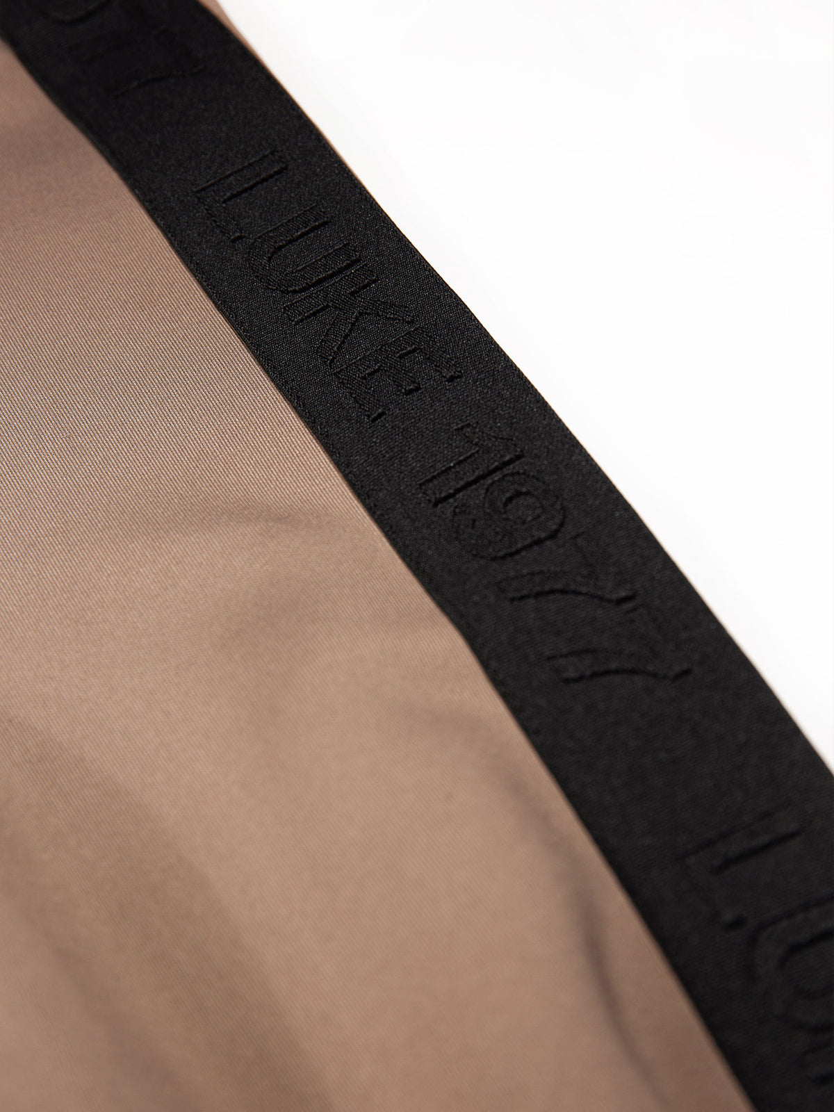 Close-up of contrast black LUKE 1977 trim tape on brown TTTQR tricot sweatshirt