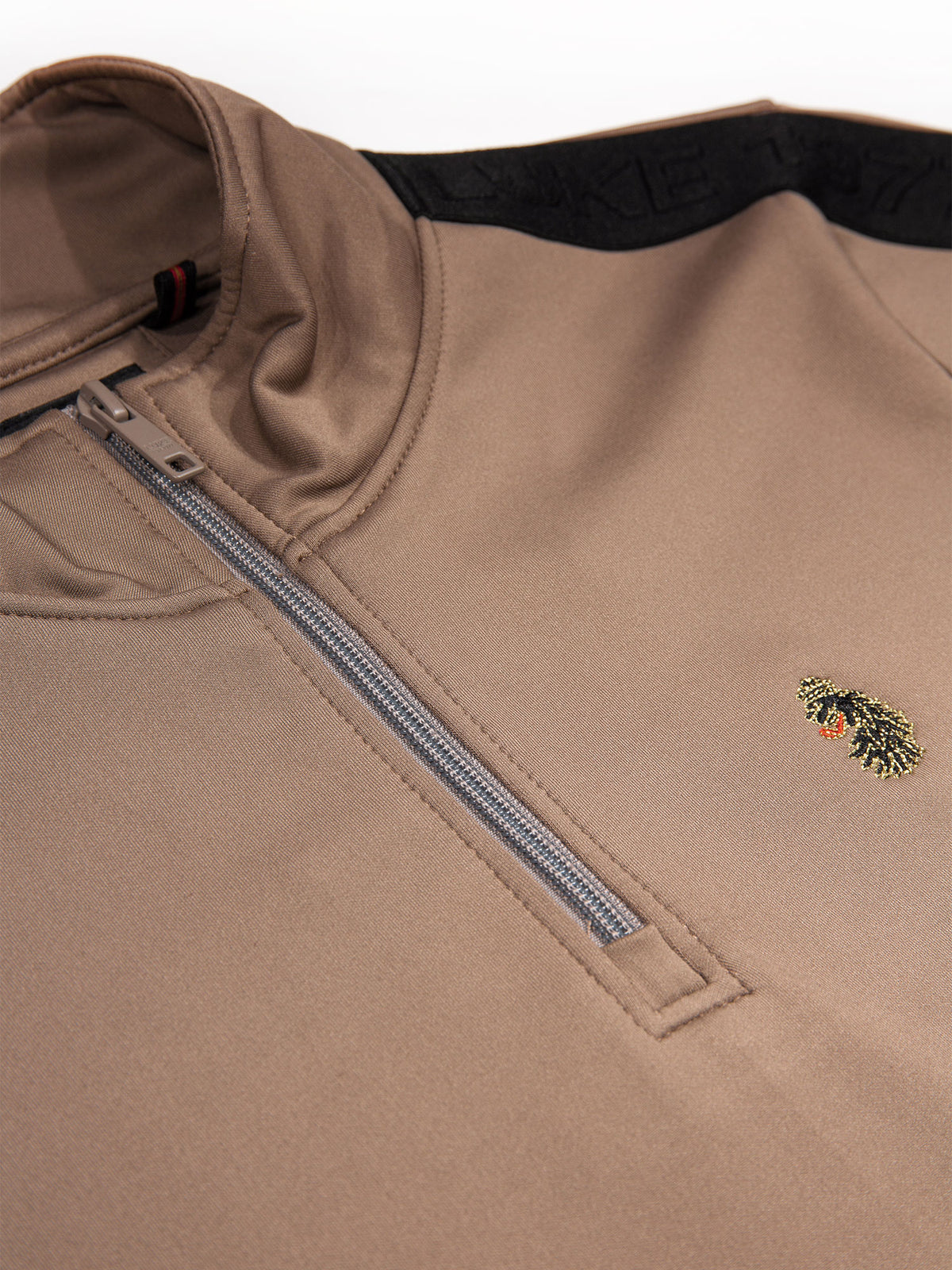 Close-up of quarter zip with tonal branded zip puller on brown TTTQR sweatshirt