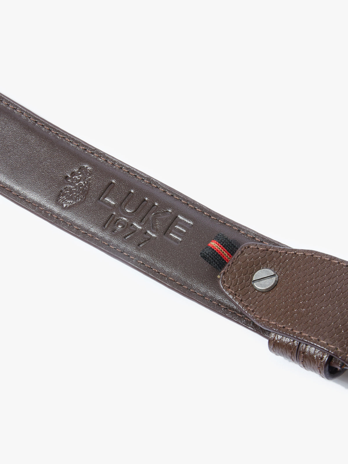 Close-up of embossed LUKE branding and metal rivet on dark brown Saturday Night belt