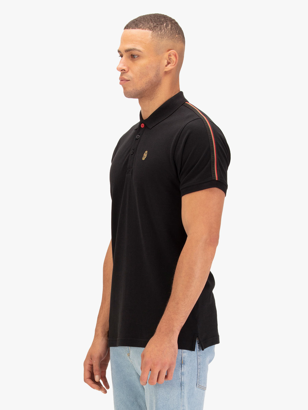Side view of man wearing black LUKE 1977 New Willtape polo with LUKE 1977 sleeve tape